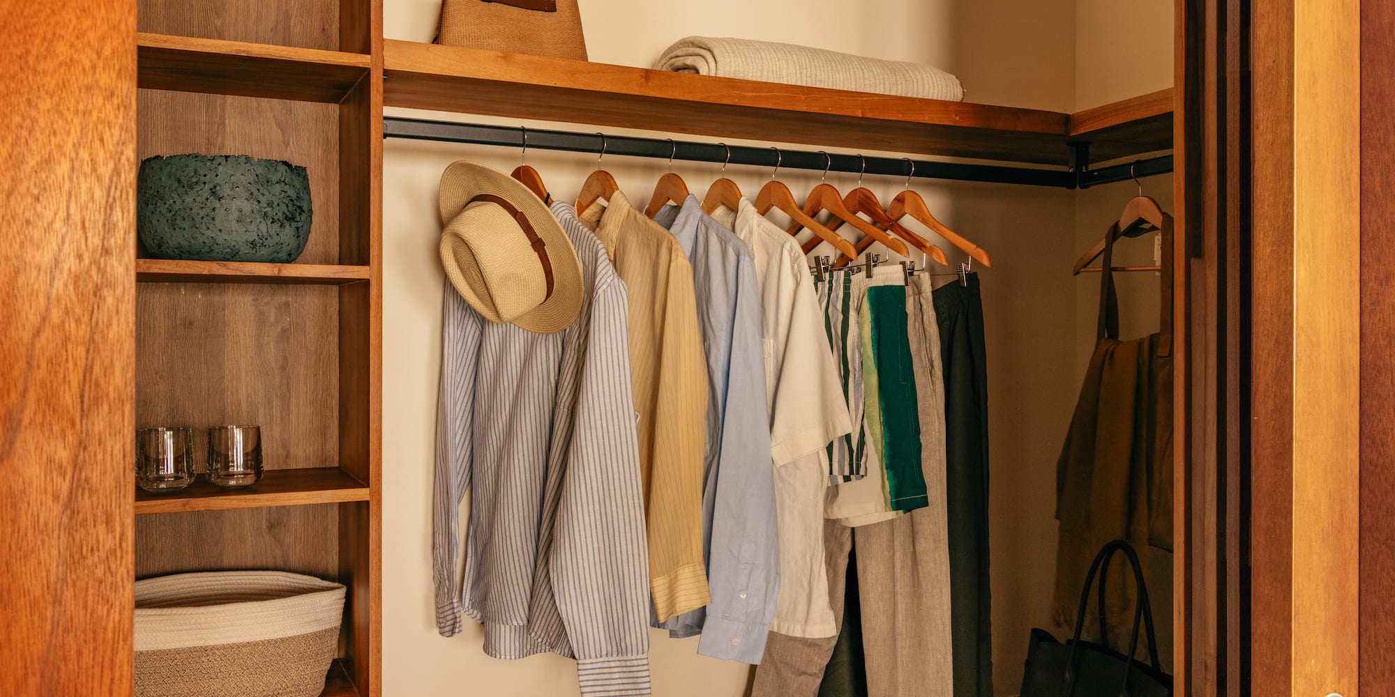 a closet with clothes on swingers and a shelf