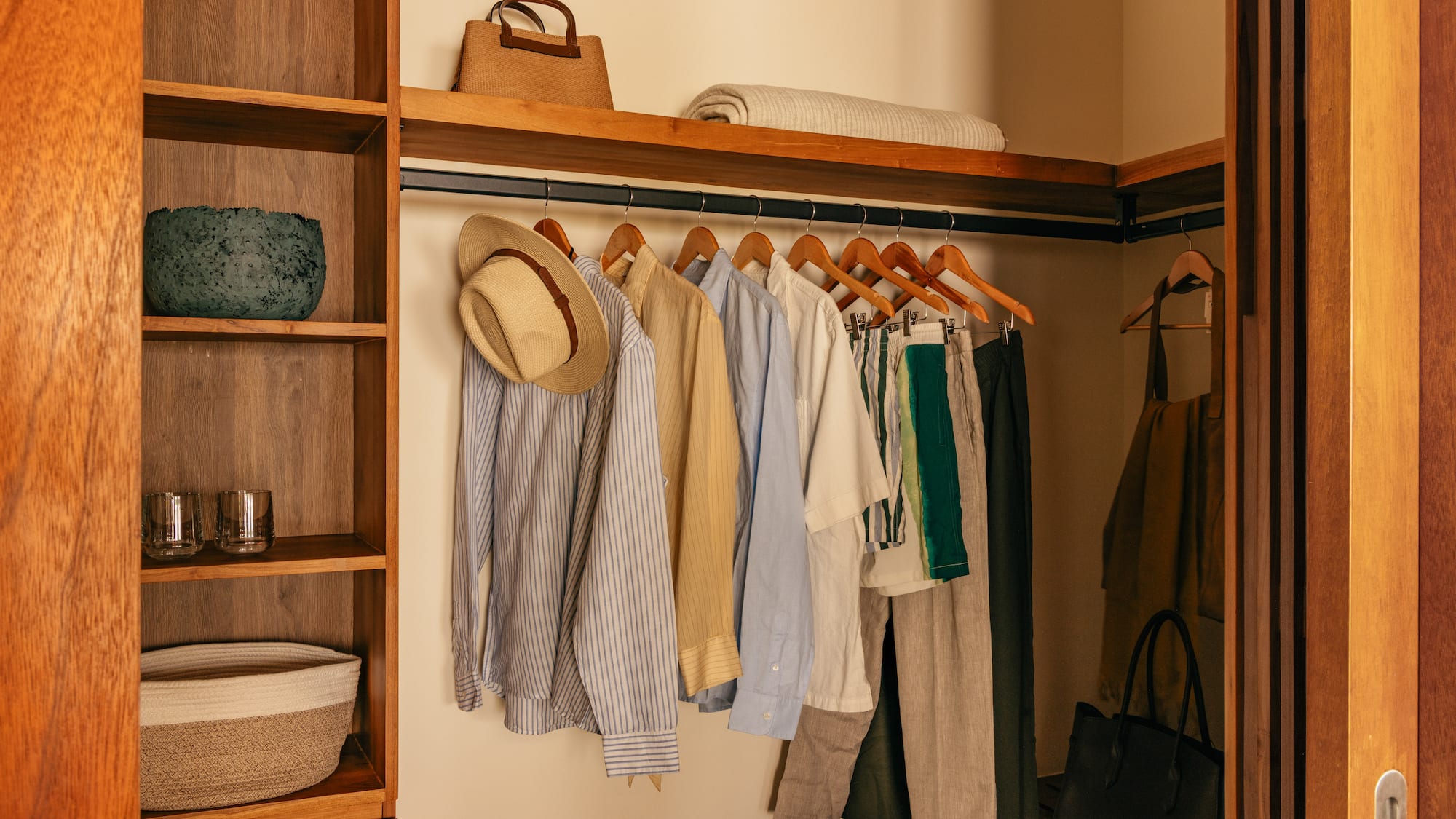 a closet with clothes on swingers and a shelf