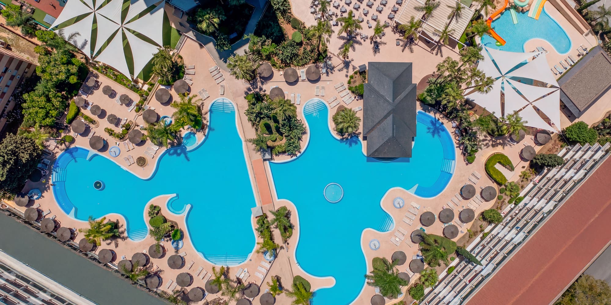 Aerial resort complex: extensive pools, sun loungers, water park, palm trees.