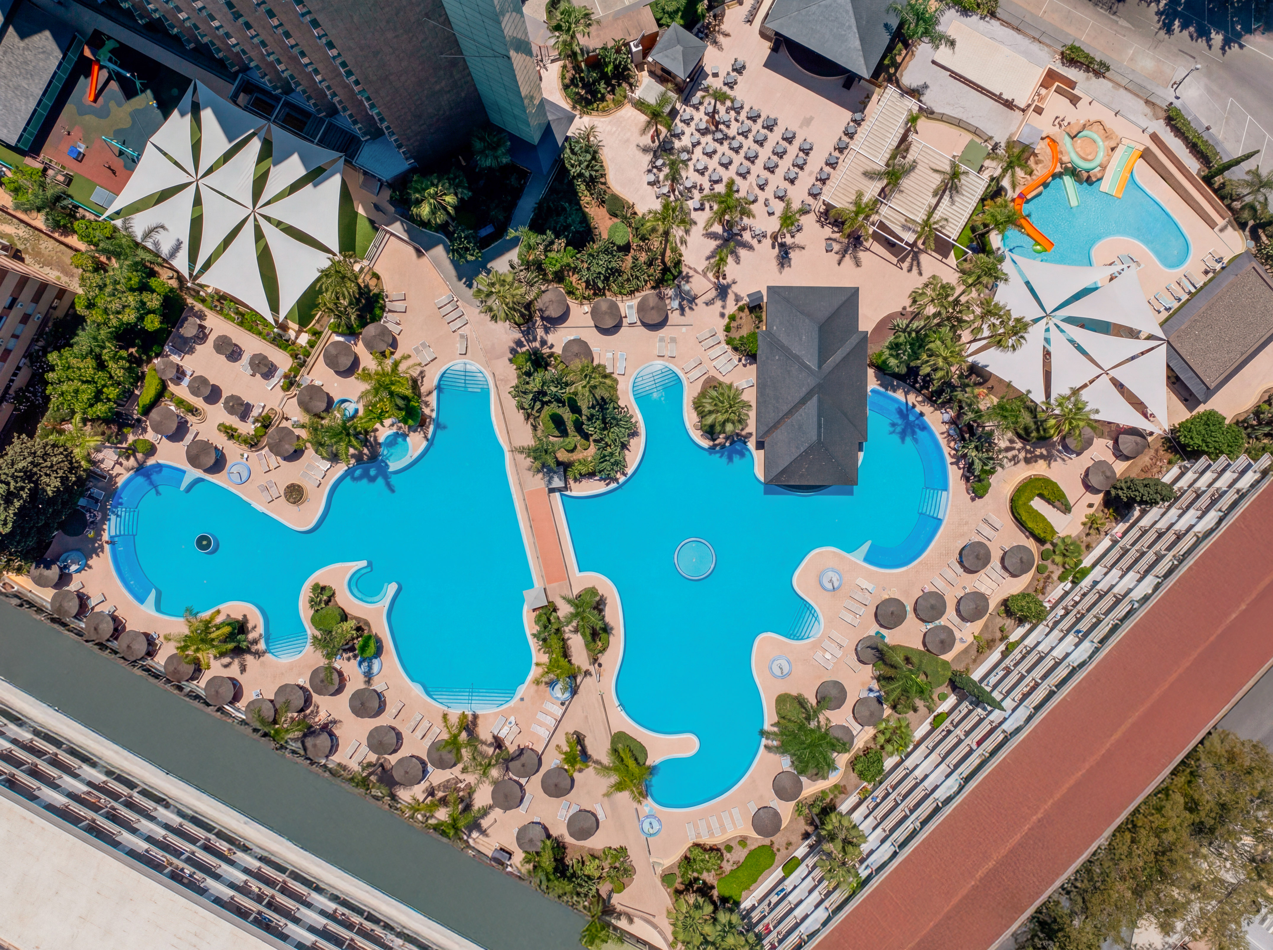 Aerial resort complex: extensive pools, sun loungers, water park, palm trees.