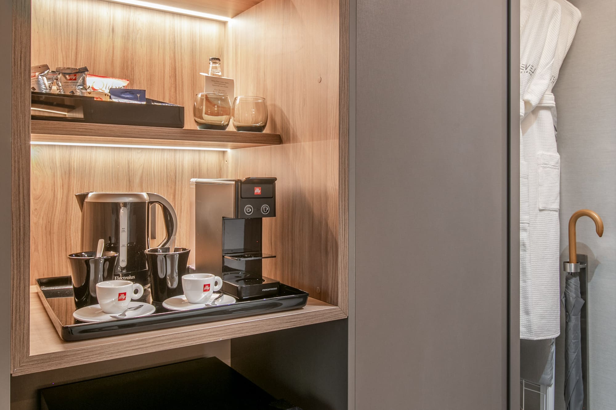 Hotel room minibar, coffee station, espresso machine, kettle, snacks, and robes.