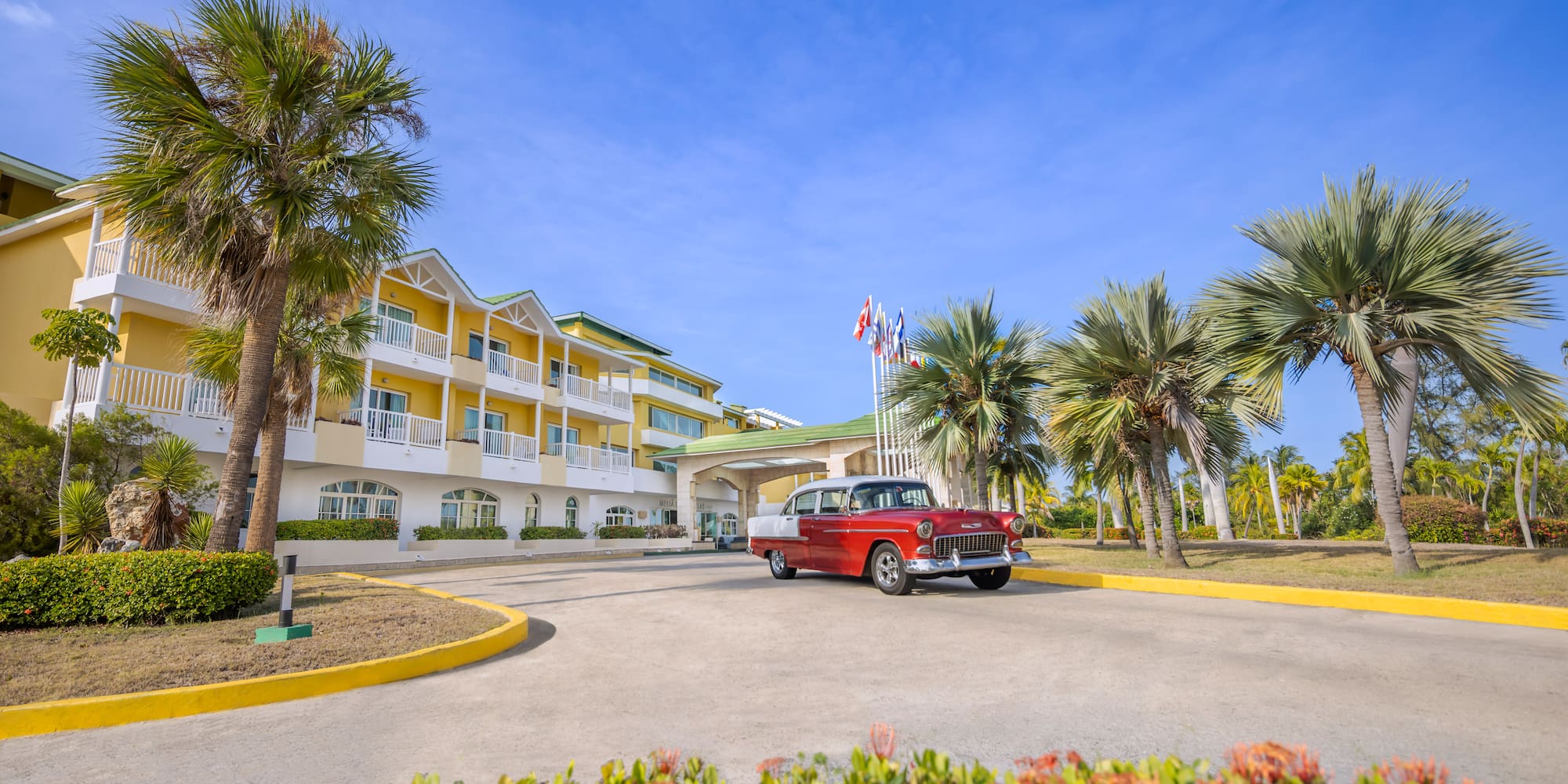a red car parked in front of a hotel