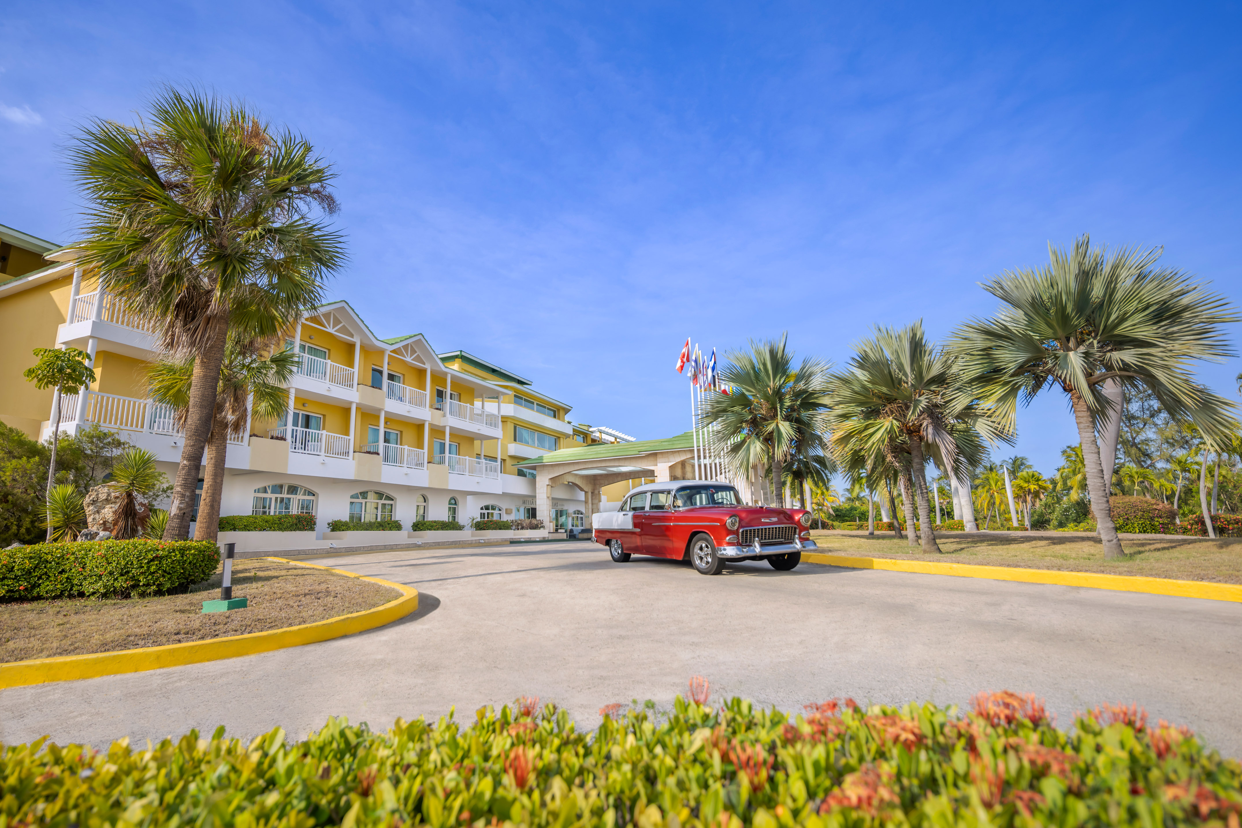 a red car parked in front of a hotel