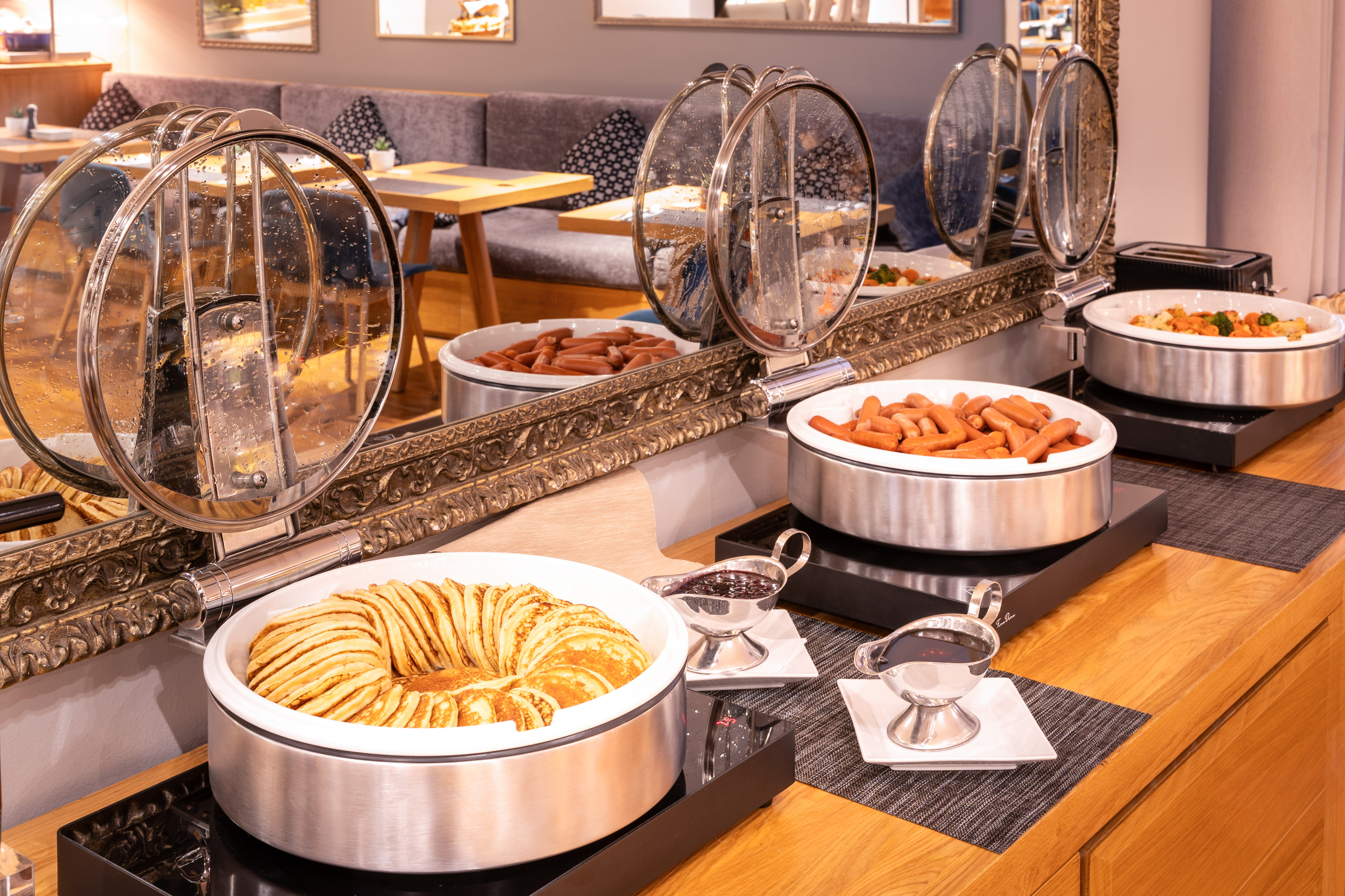 Hotel breakfast buffet with warm pancakes, sausages, and hot food.
