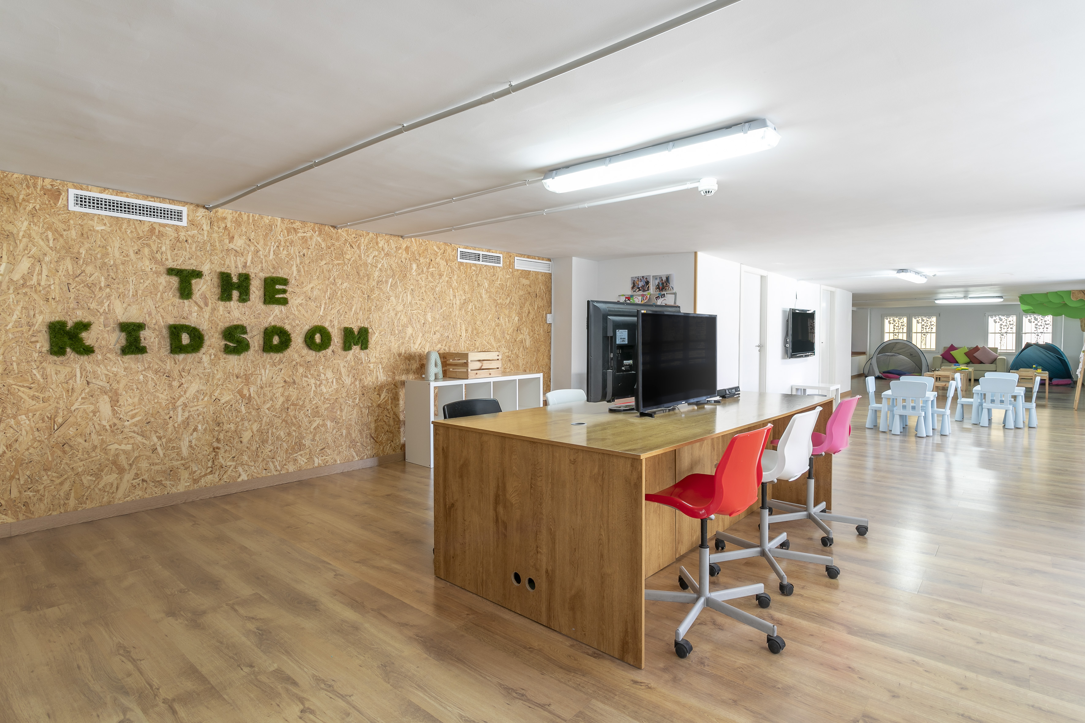 The Kidsdom kids' playroom with moss wall, wooden desk, and colorful furniture.