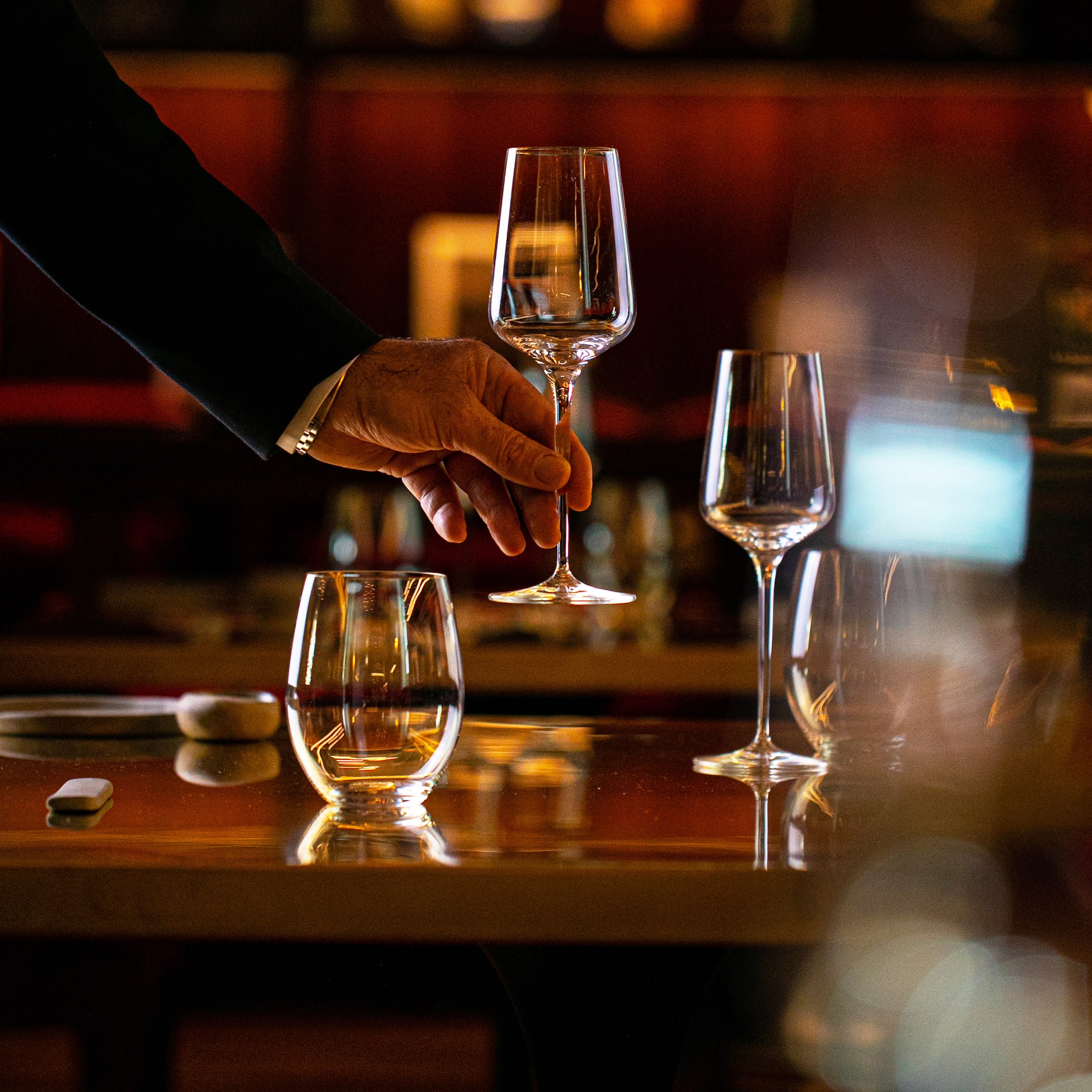 a hand holding a wine glass over a table