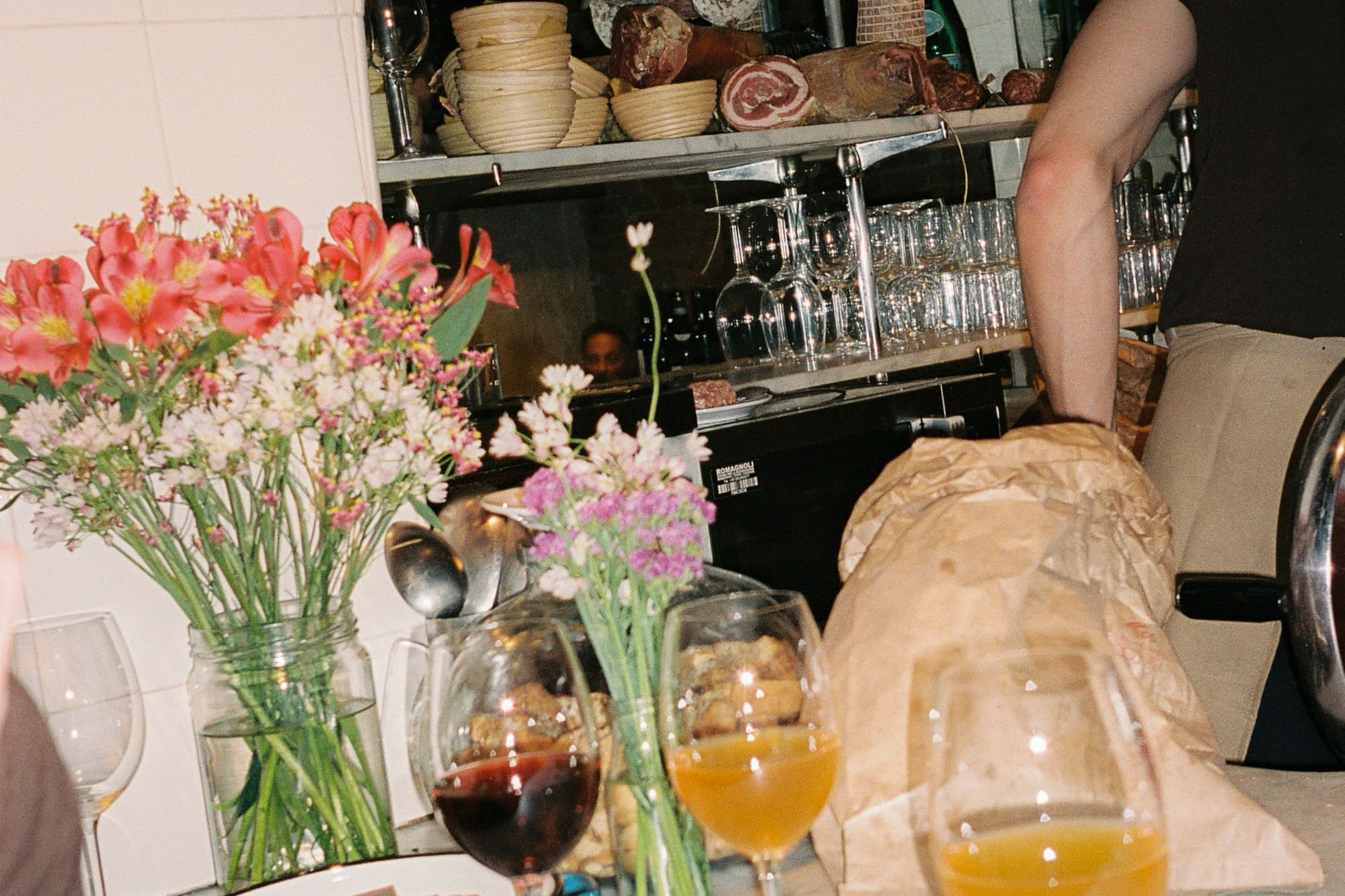 a man standing at a table with wine glasses and flowers