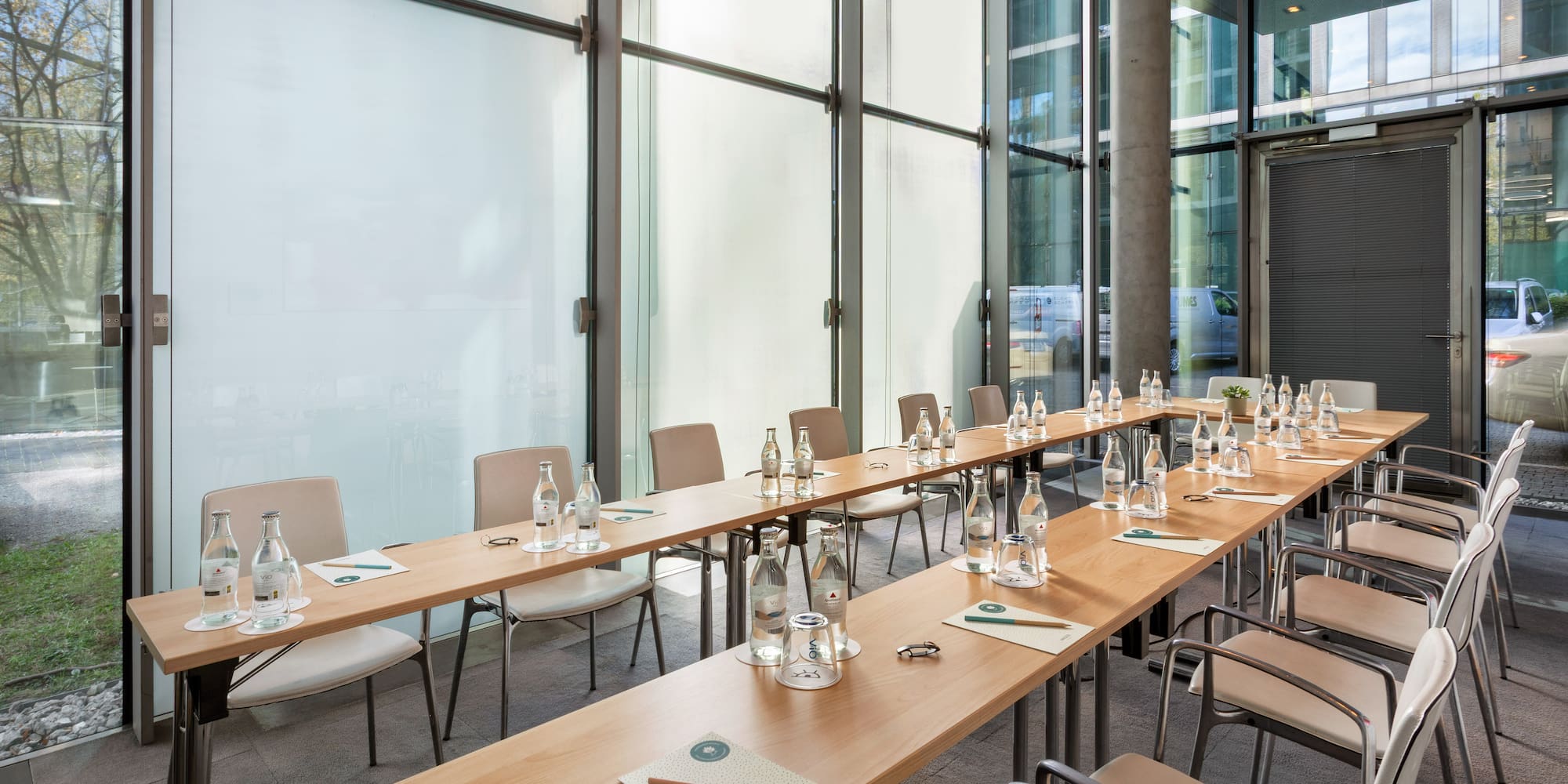 a long table with water bottles and chairs in a room with windows