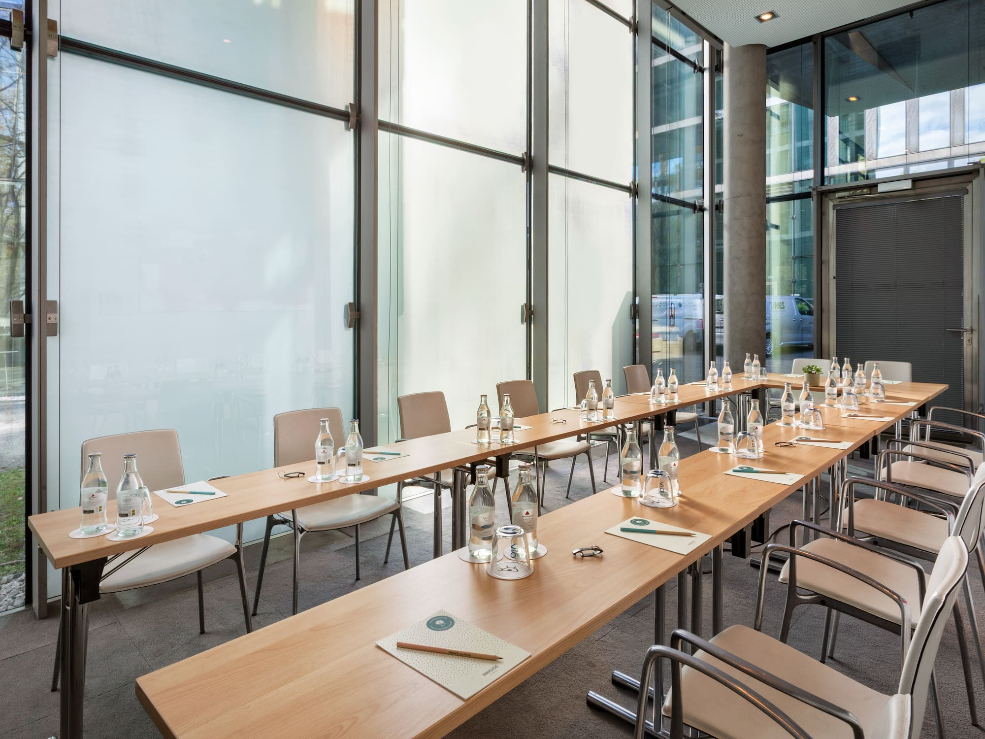 a long table with water bottles and chairs in a room with windows