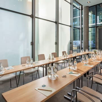 a long table with water bottles and chairs in a room with windows