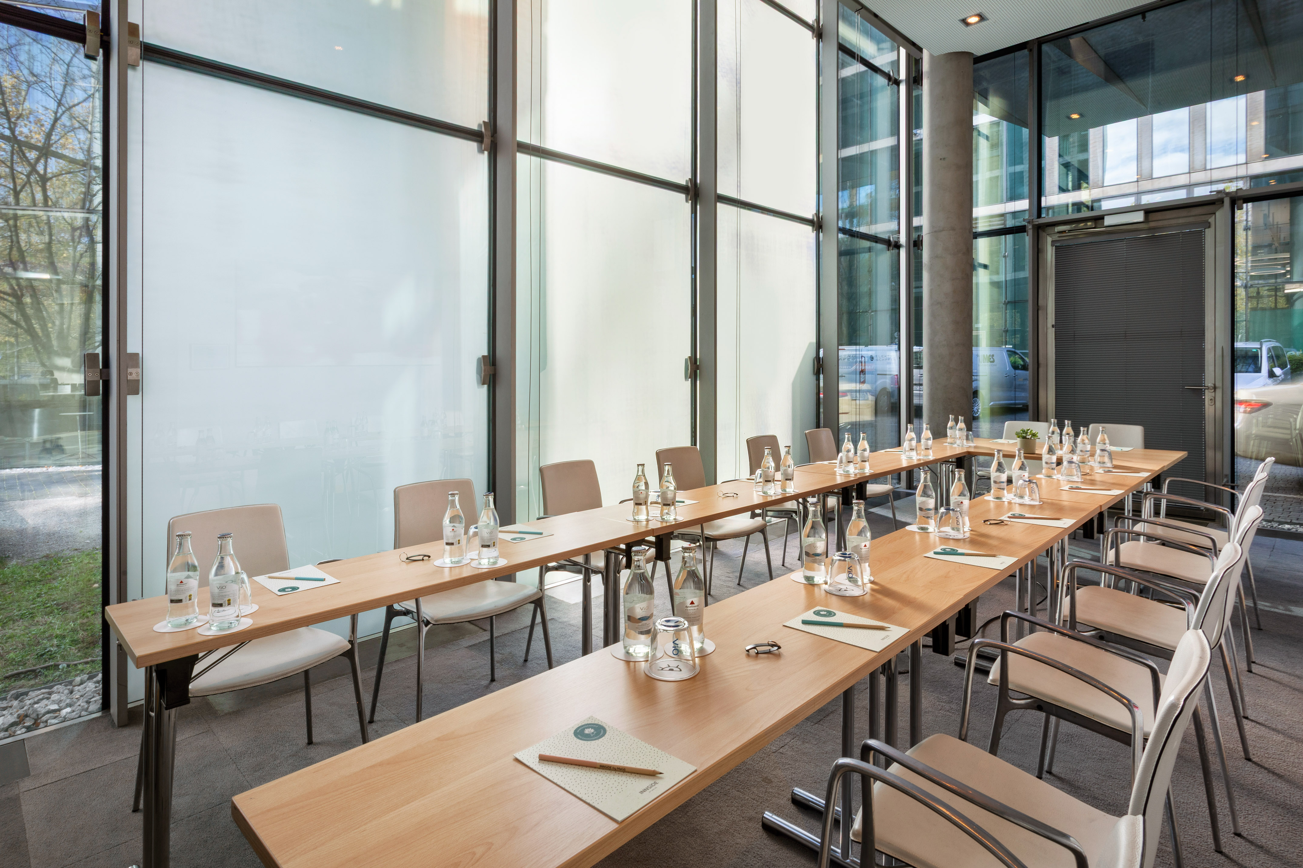 a long table with water bottles and chairs in a room with windows