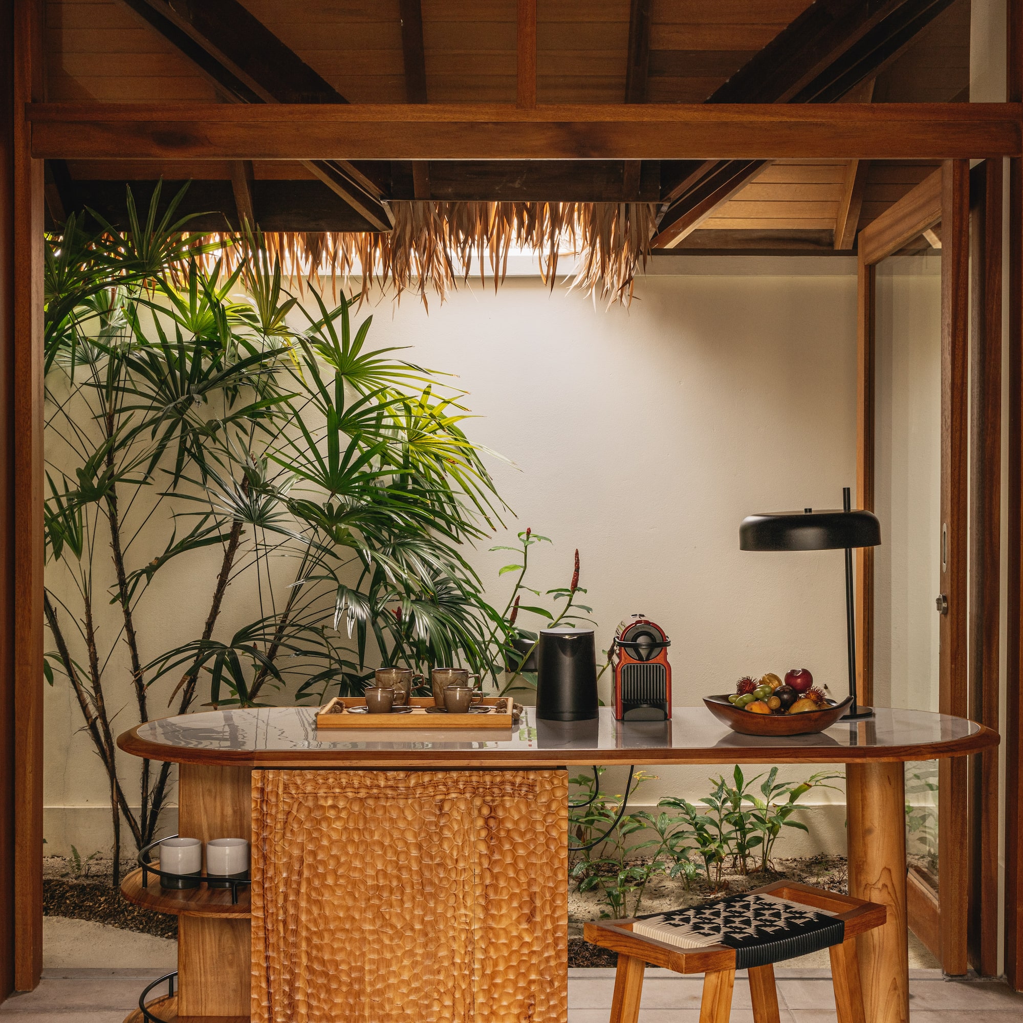 a table with a lamp and a table with a plant in the background