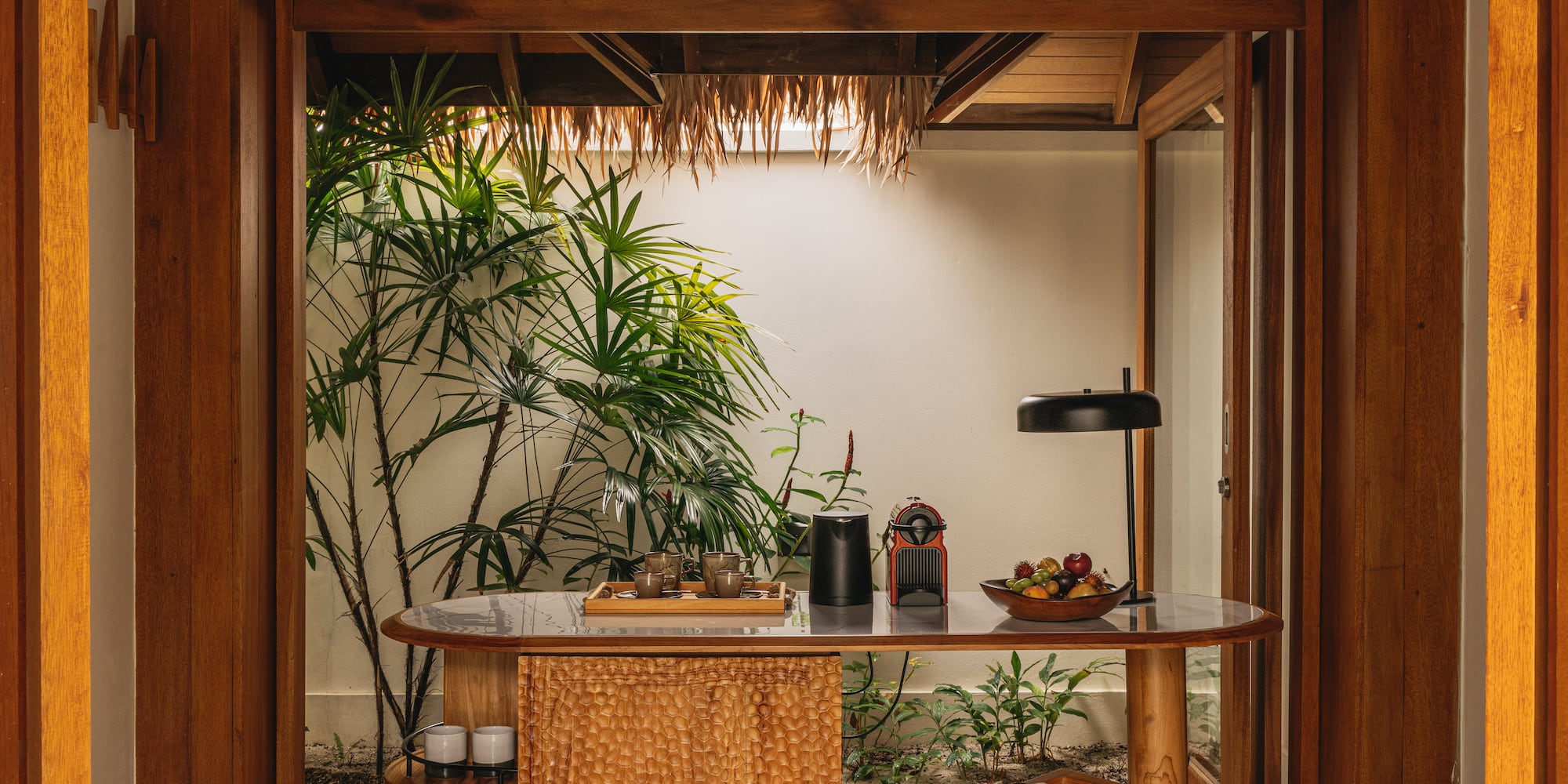 a table with a lamp and a table with a plant in the background
