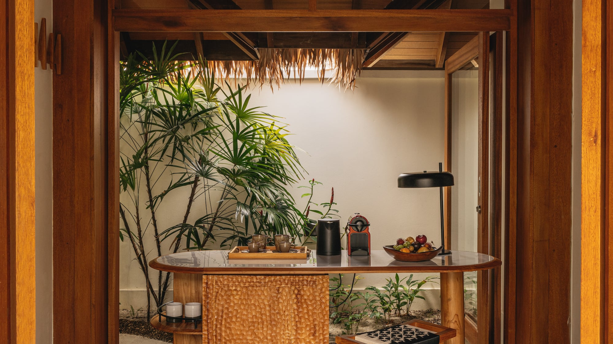 a table with a lamp and a table with a plant in the background