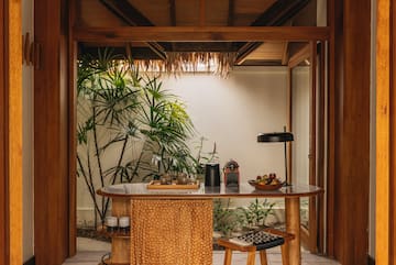 a table with a lamp and a table with a plant in the background