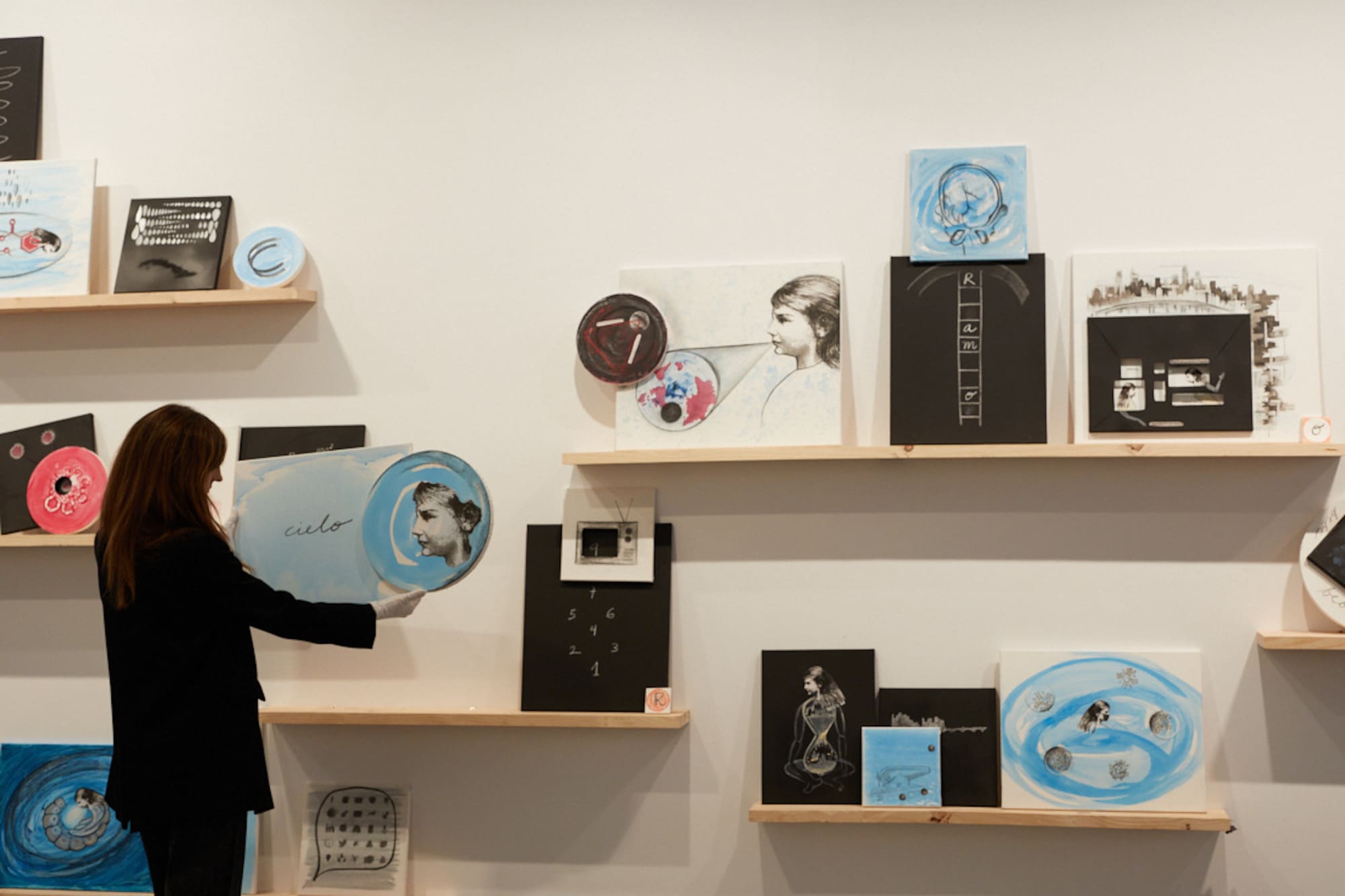 A woman stands before a wall decorated with pictures.