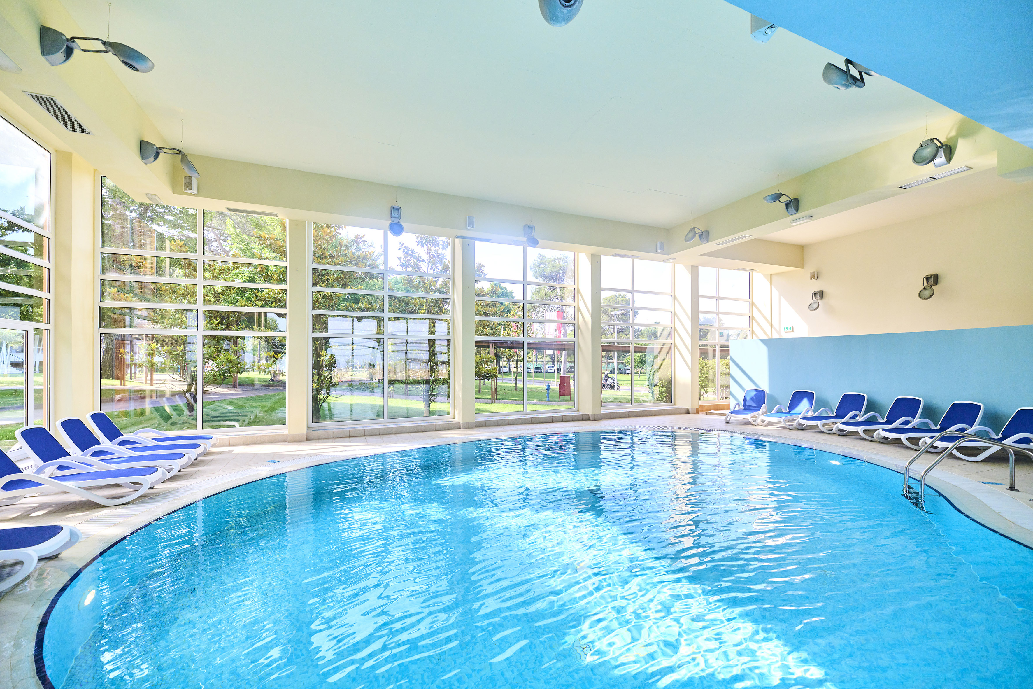 a swimming pool with chairs in a room with windows
