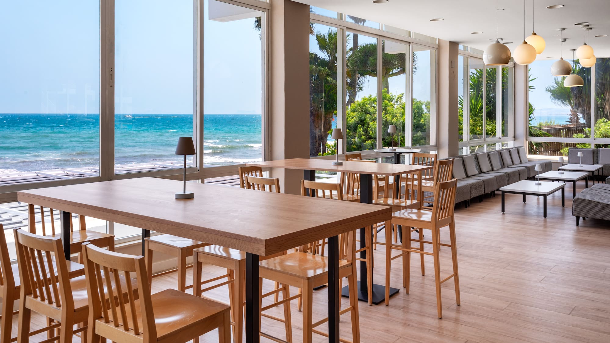 a room with tables and chairs and a view of the ocean