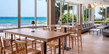 a room with tables and chairs and a view of the ocean