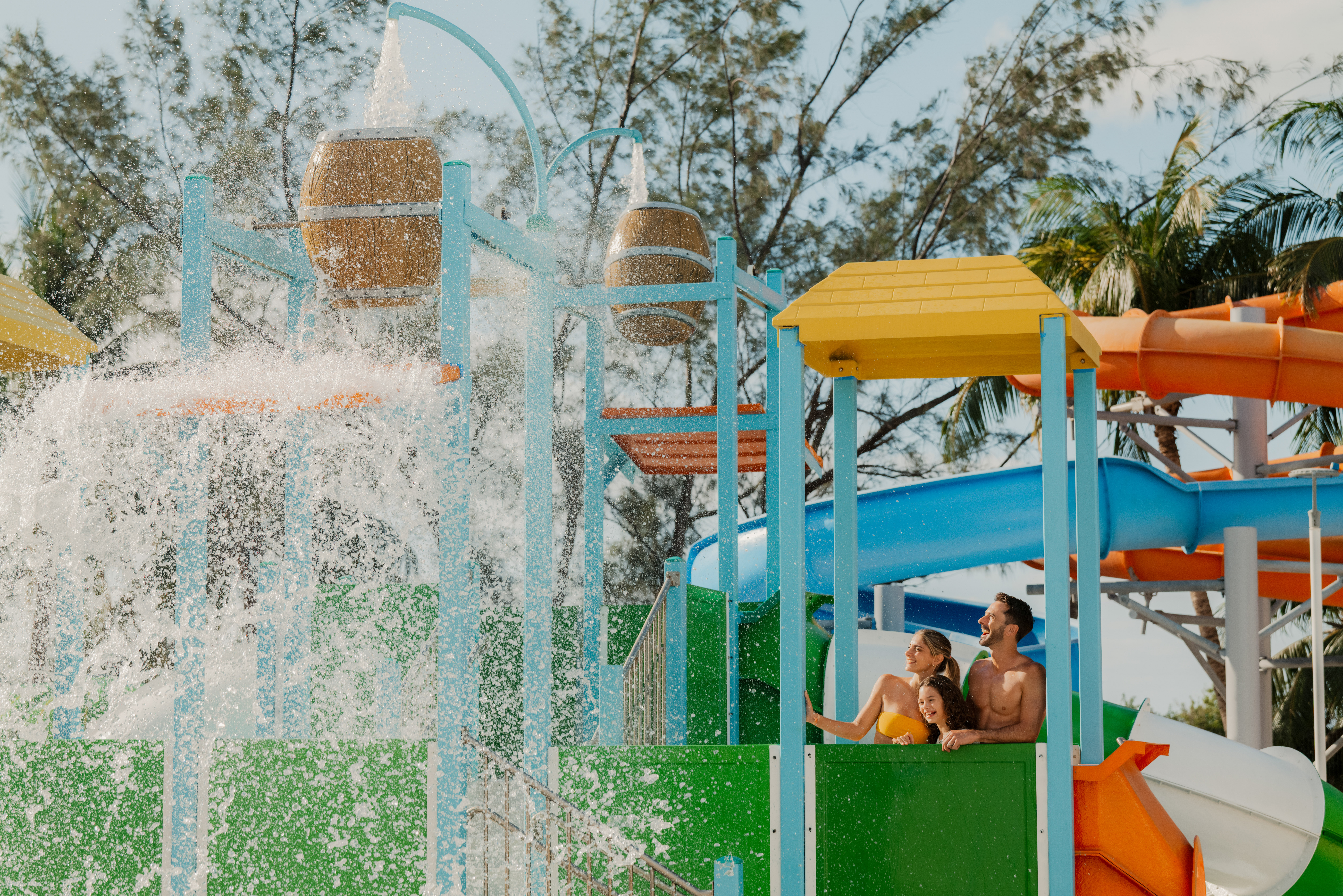 Smiling family experiencing a huge splash at a vibrant water park.