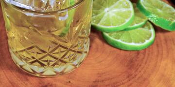 a glass of ice and limes on a wood surface