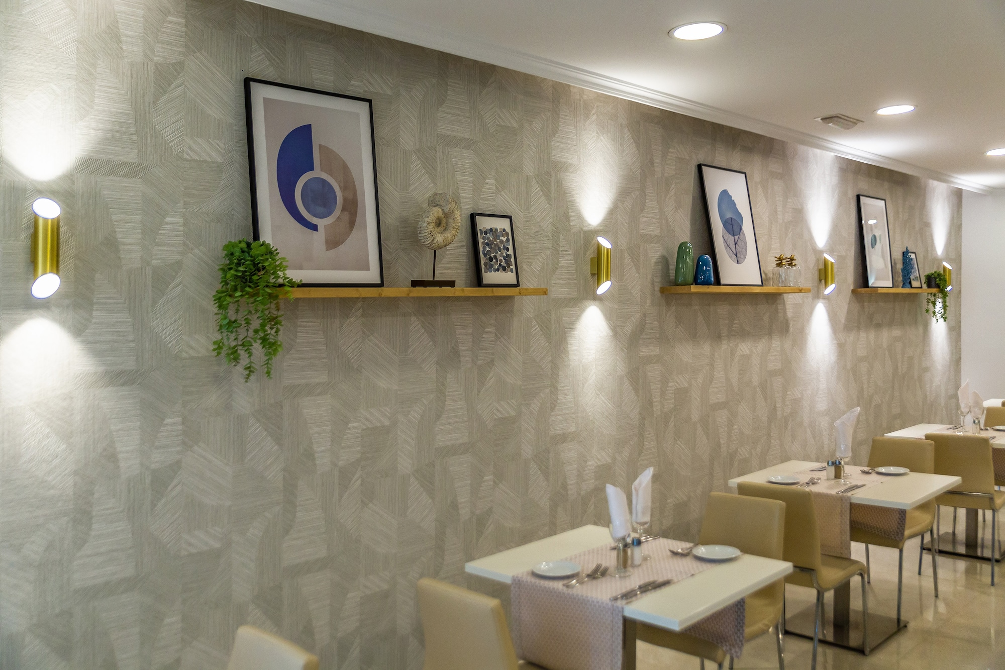 Restaurant interior with patterned wall, art display shelves, and ambient lighting.