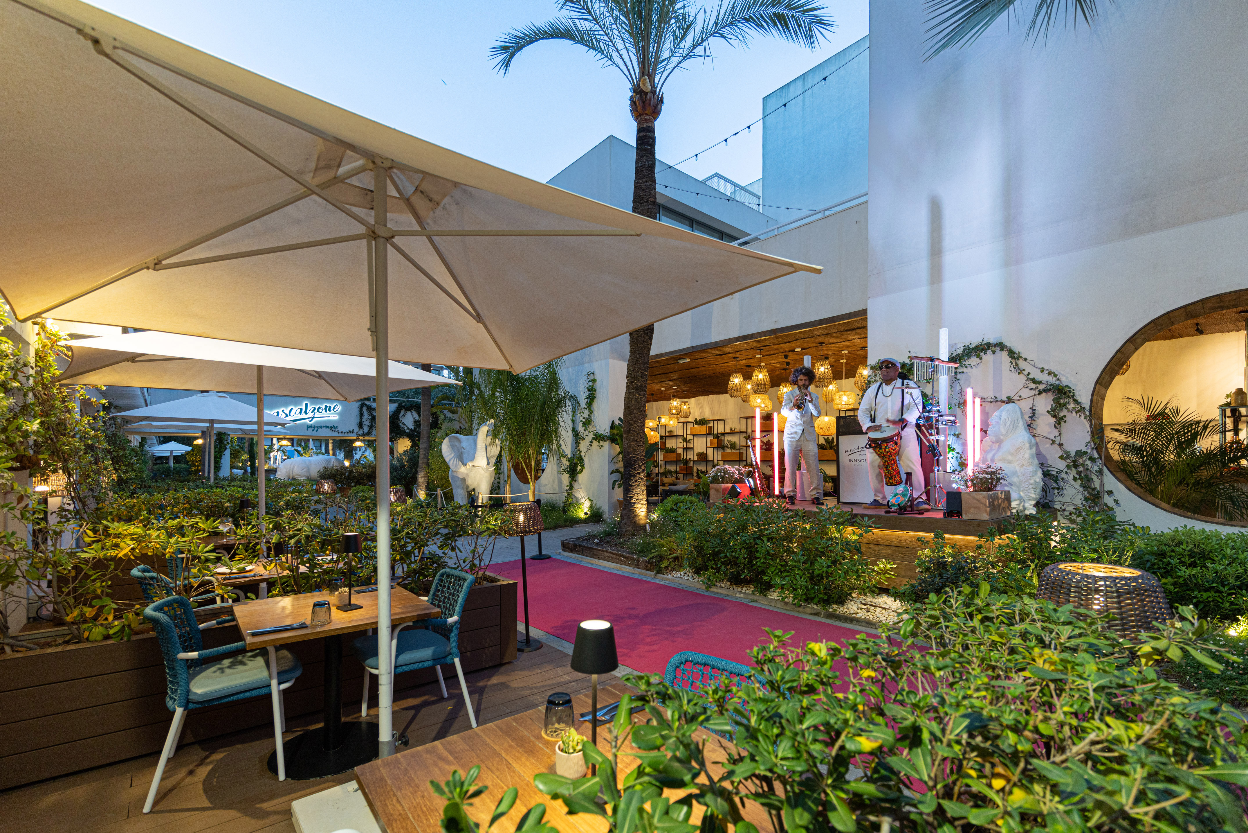 Outdoor restaurant patio, live music, red carpet event at dusk.