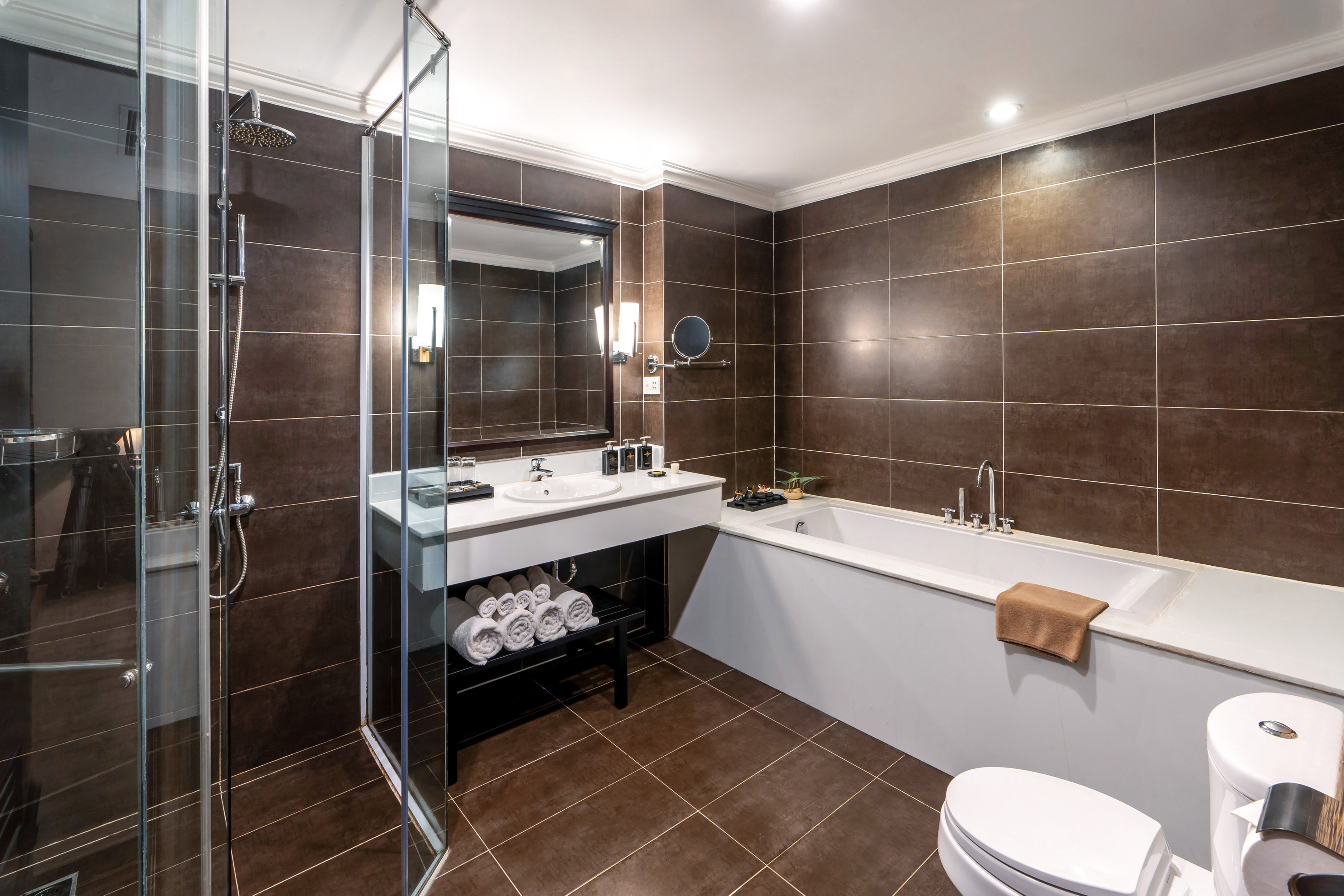 Hotel bathroom with dark brown tiles, glass shower, bathtub, and vanity. - Junior Suite - Hotel Sapa Square Affiliated by Meliá, Sapa