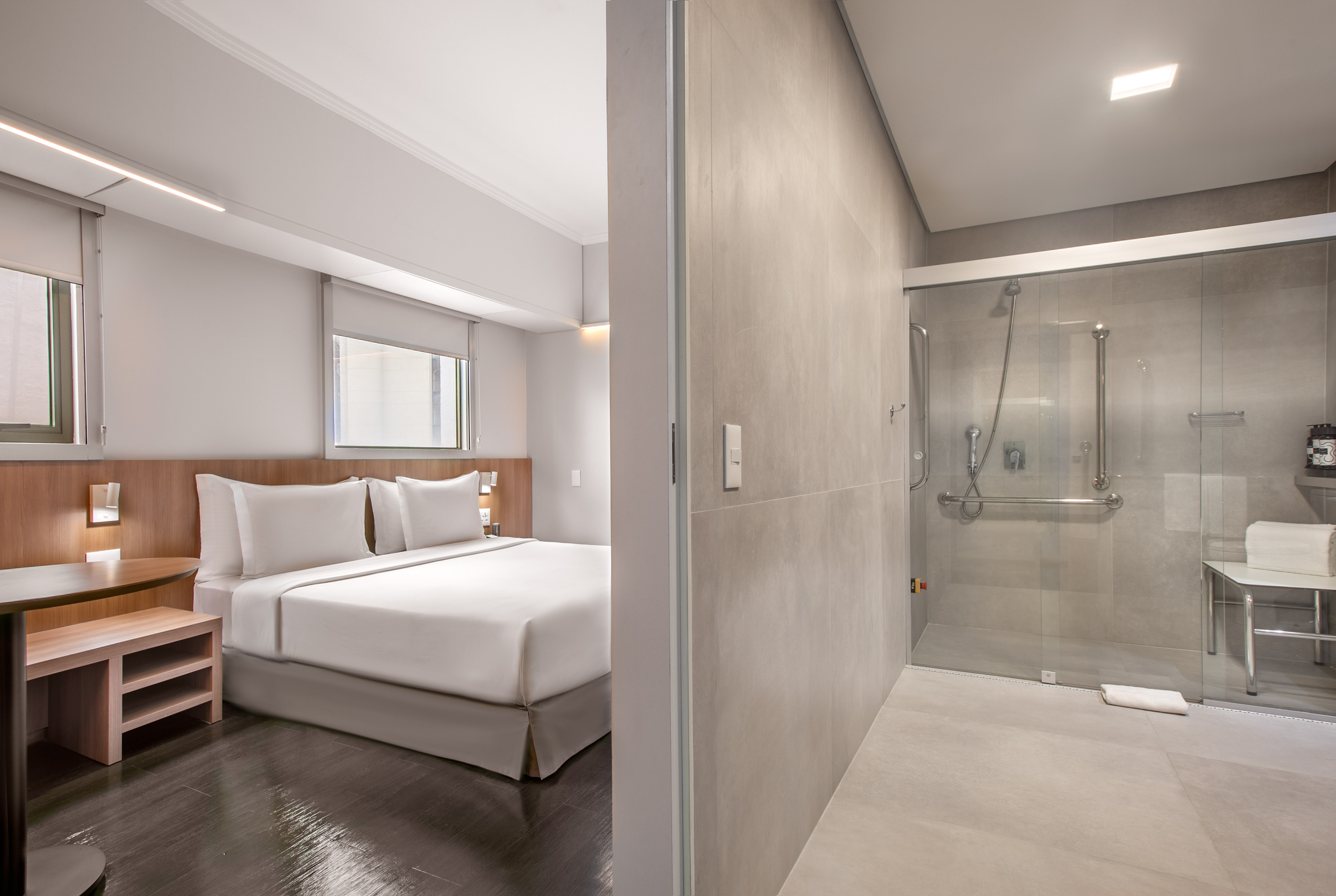 Modern hotel bedroom and accessible bathroom with walk-in shower.