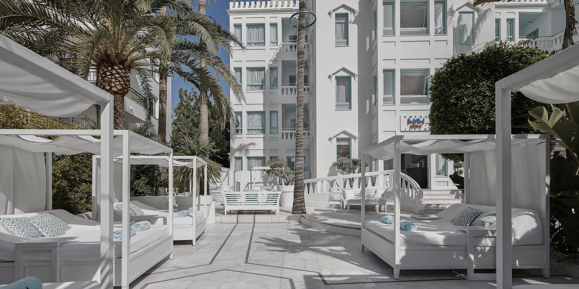 a white building with white beds and palm trees