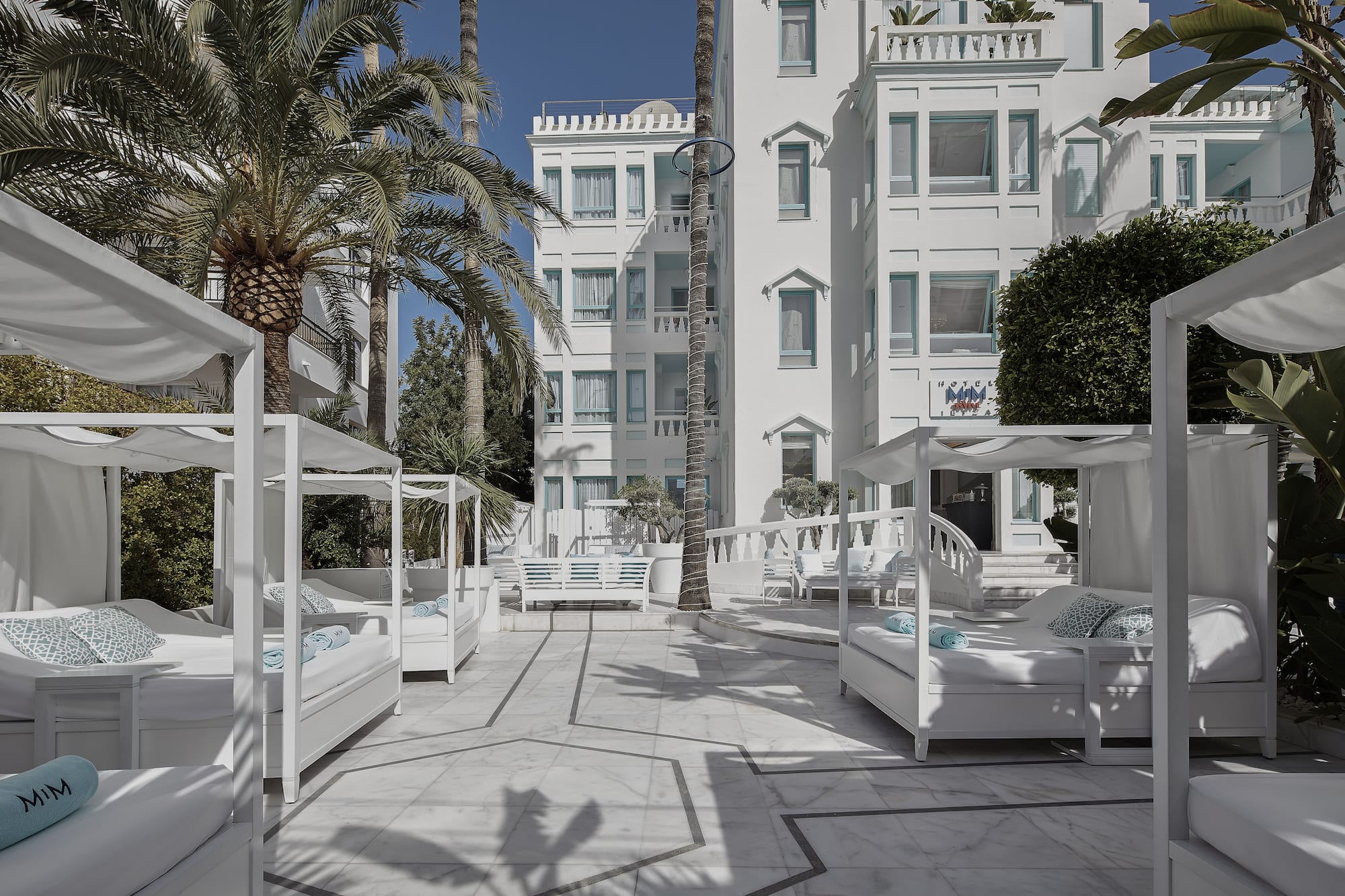 a white building with white beds and palm trees