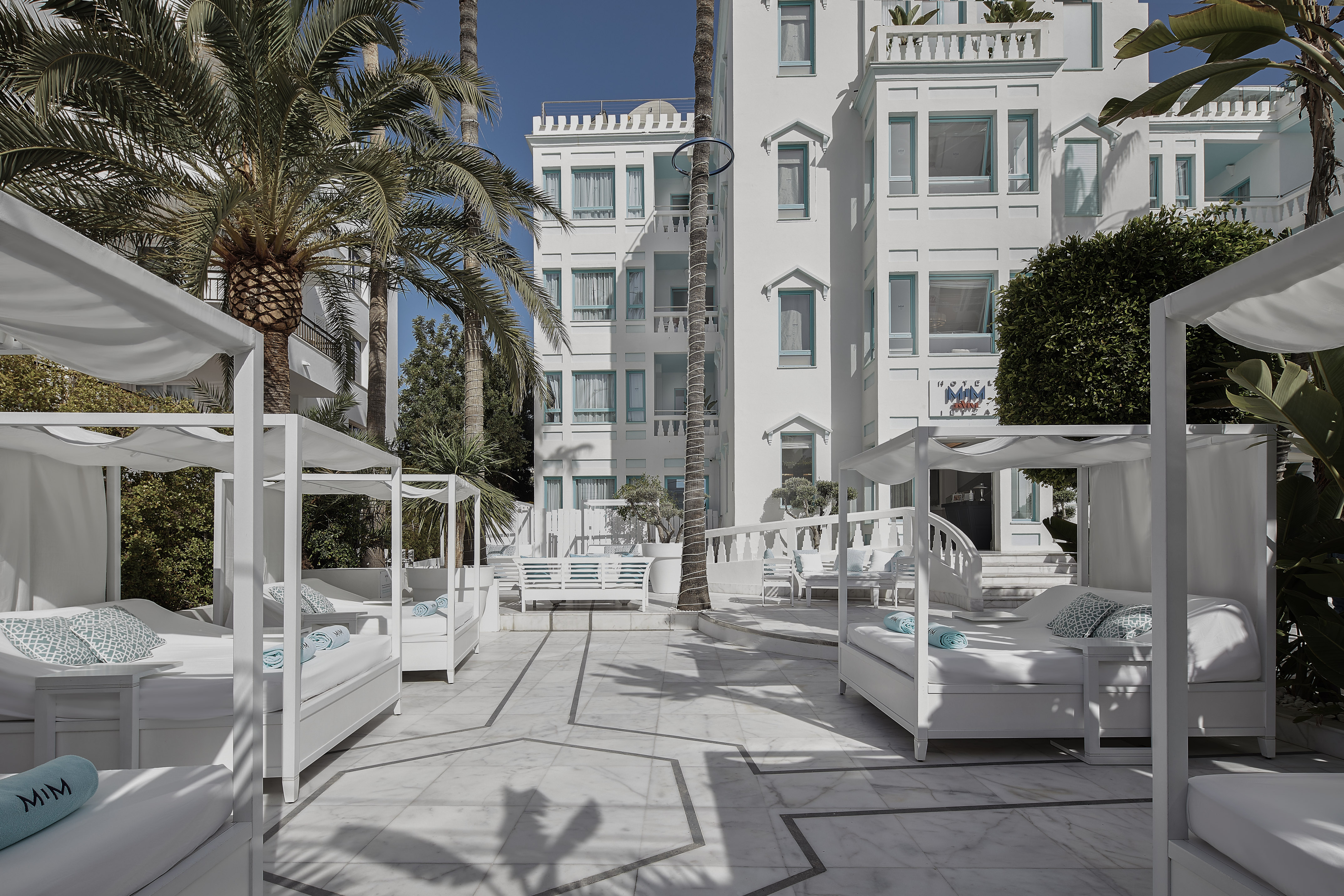a white building with white beds and palm trees
