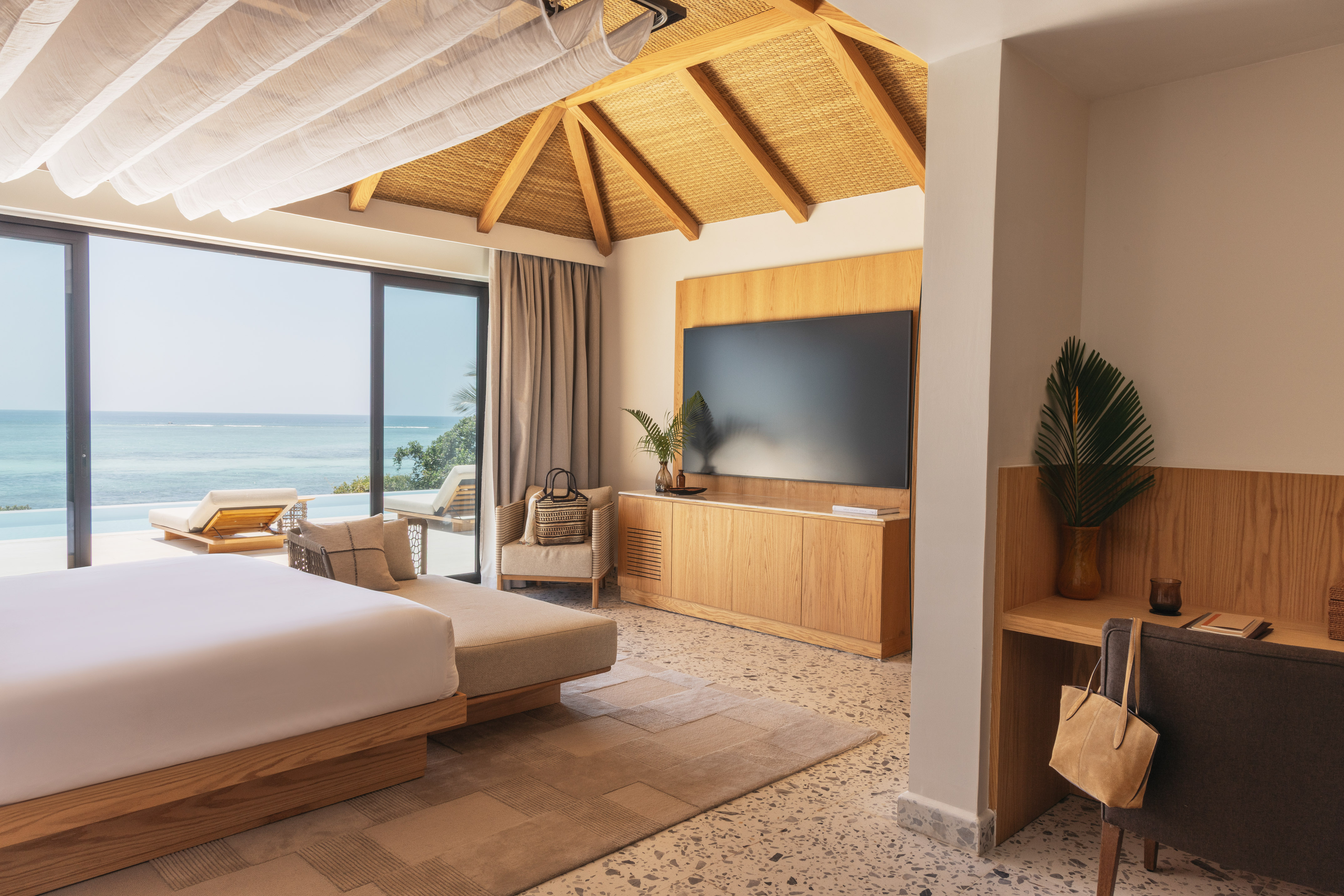 Luxury ocean view resort bedroom with modern design, bed, and private terrace.