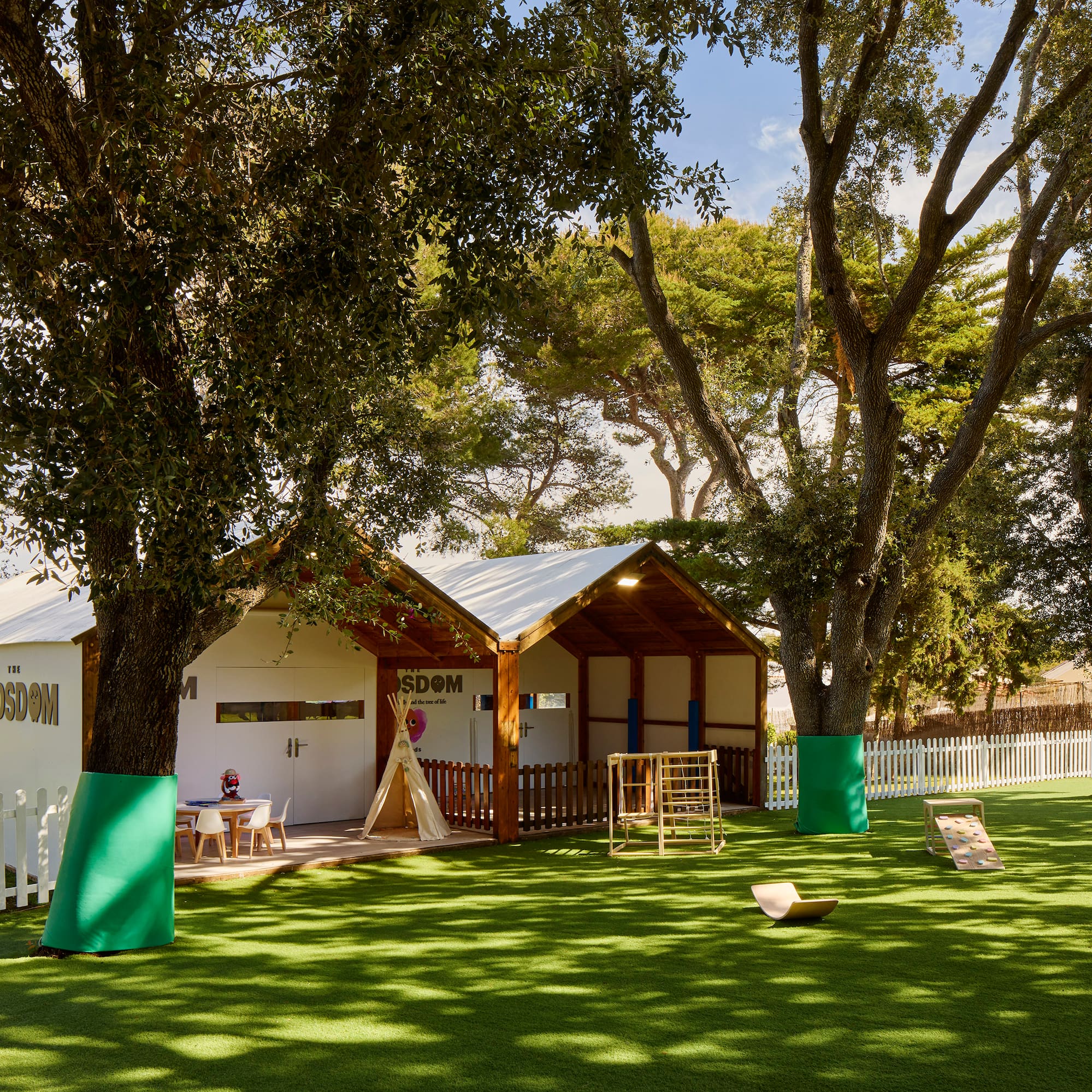 a small building with a playground in the middle of a grassy area