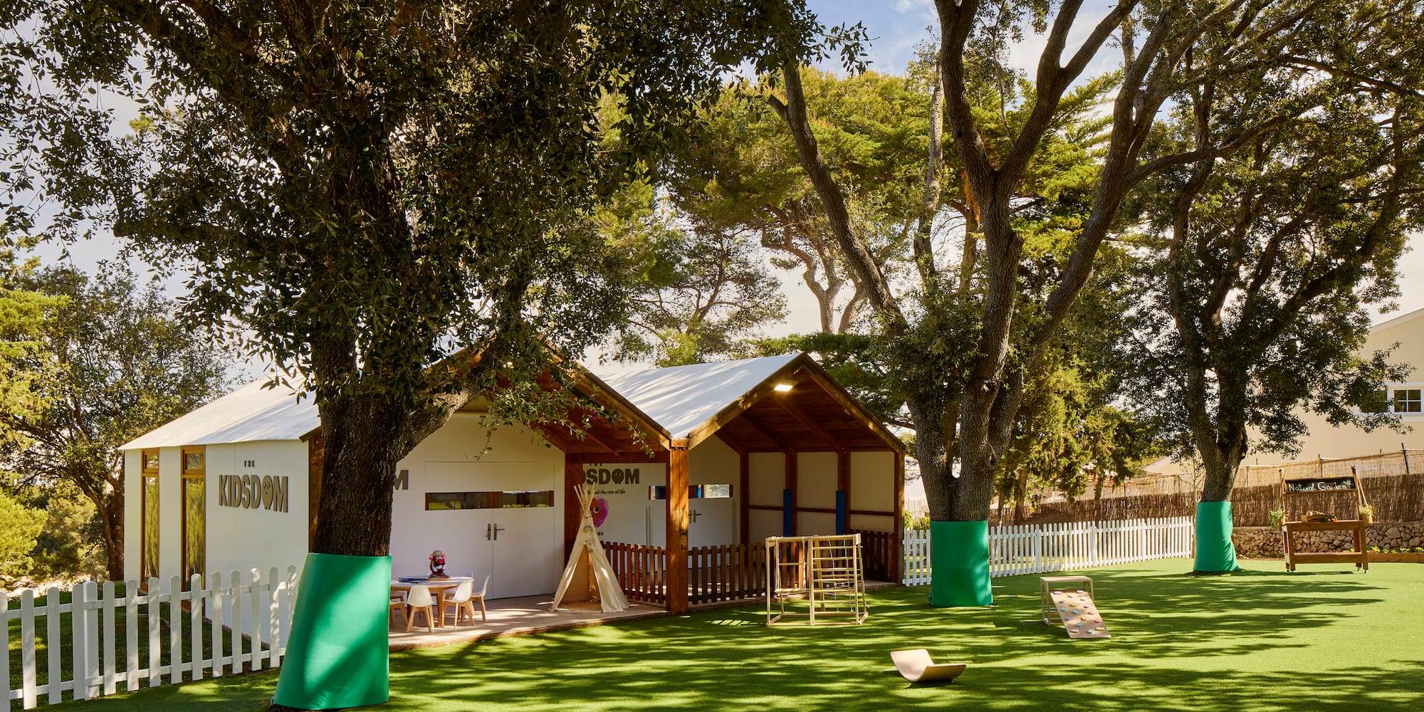 a small building with a playground in the middle of a grassy area