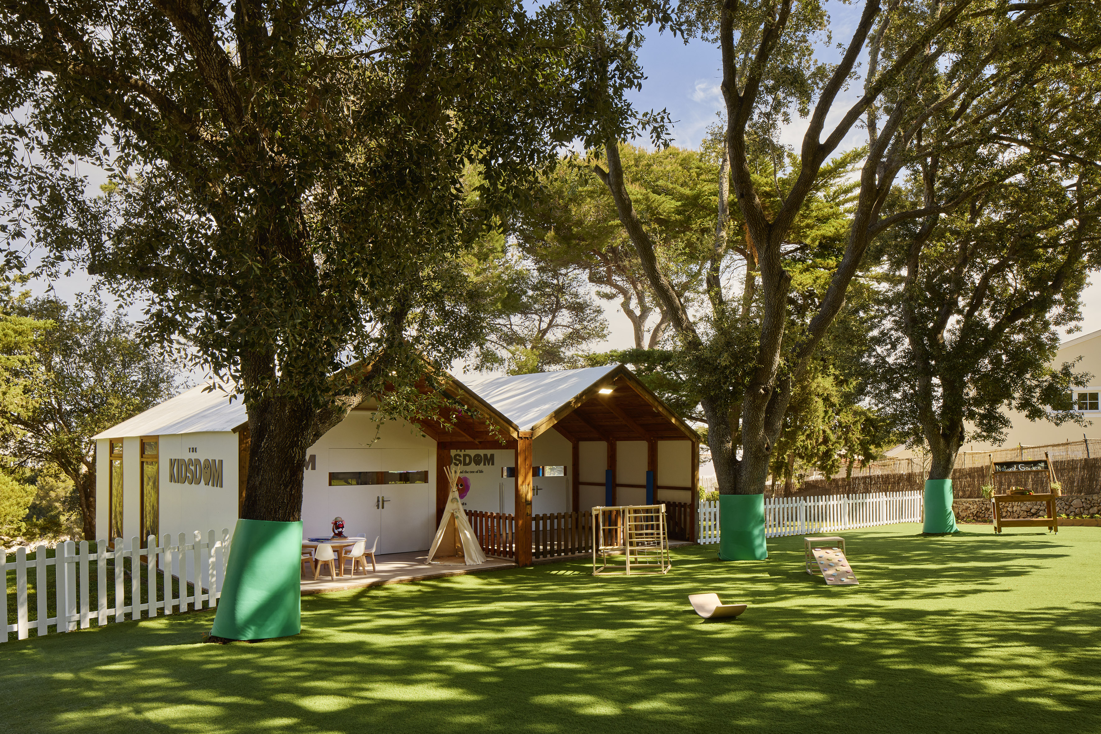 a small building with a playground in the middle of a grassy area