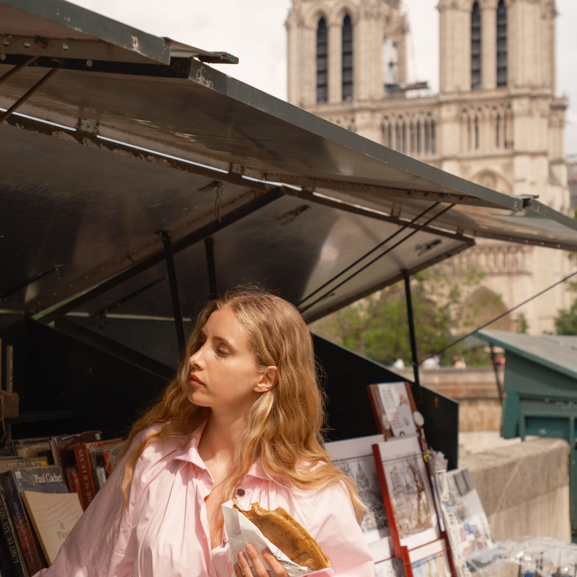 a woman standing under a tent with a sandwich