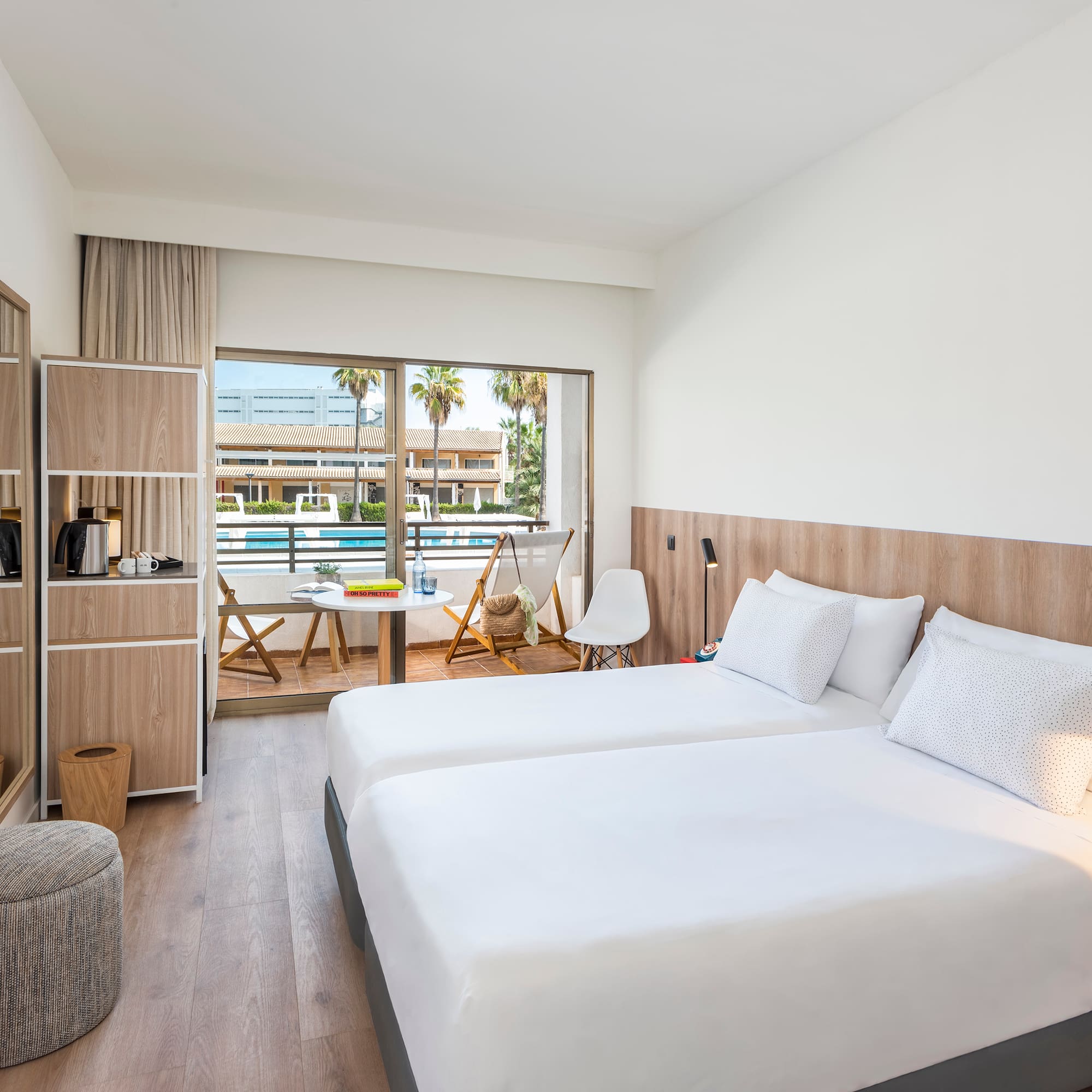 Modern hotel room with twin beds, private balcony, and pool view.