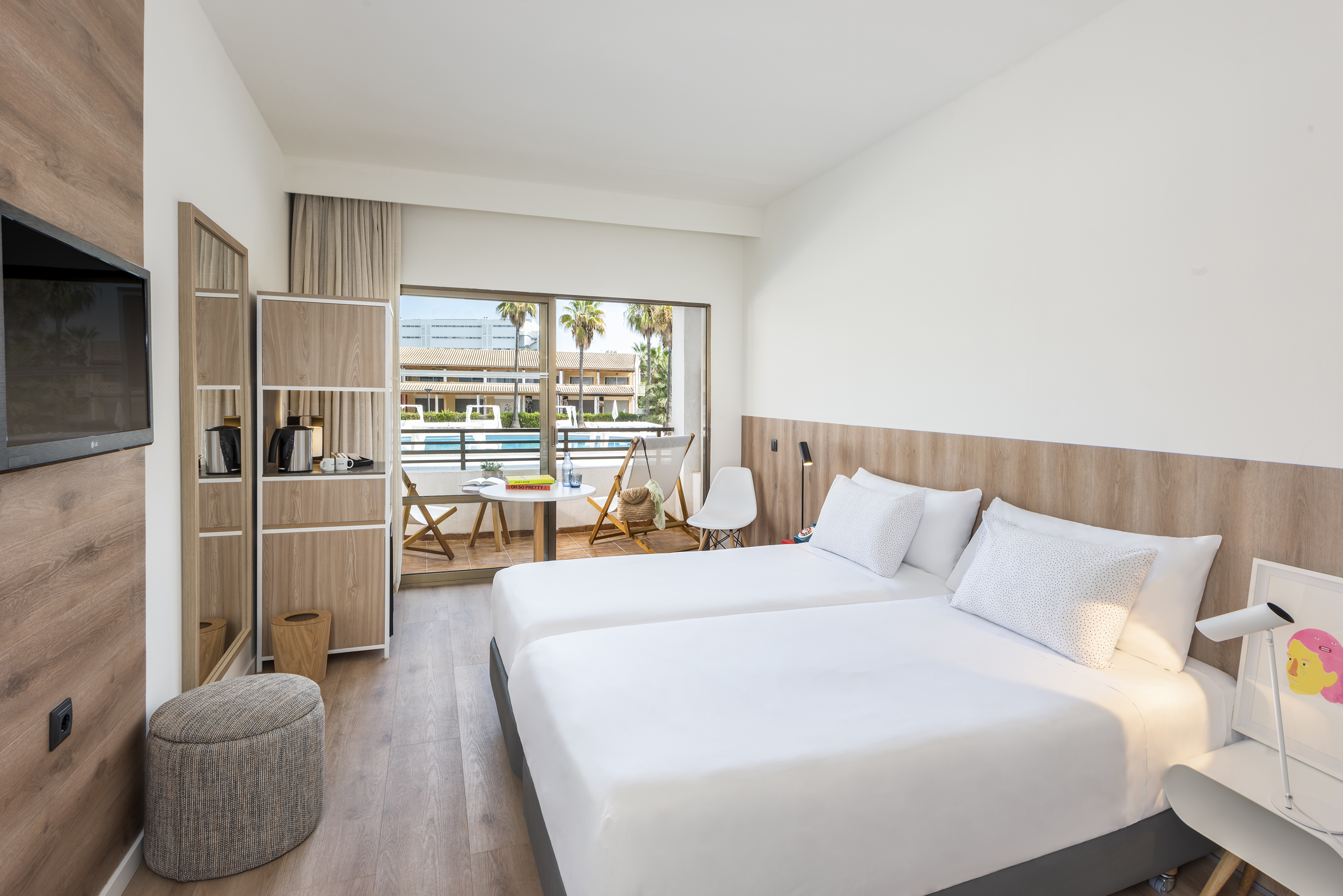 Modern hotel room with twin beds, private balcony, and pool view.
