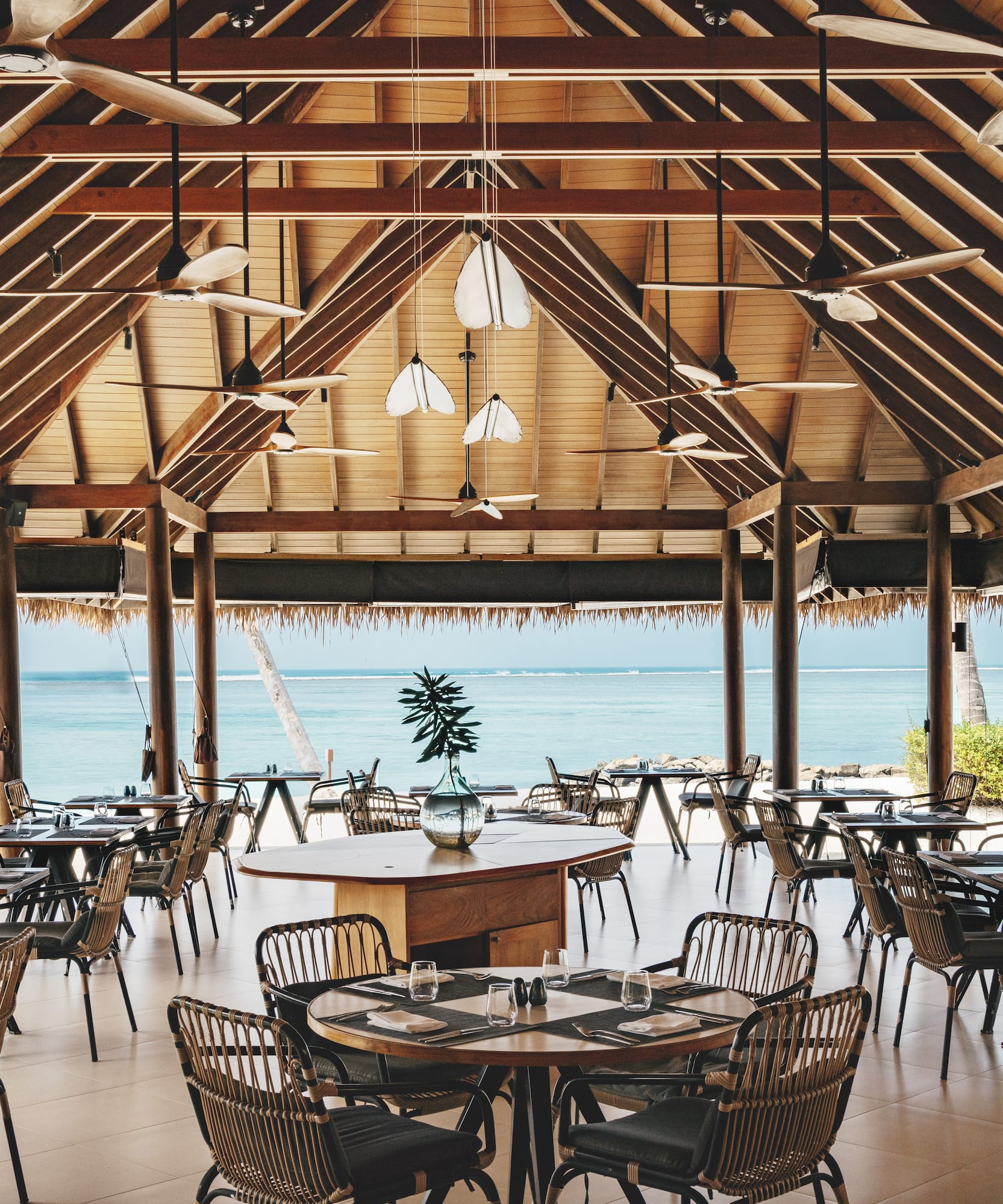 a room with tables and chairs and a view of the ocean