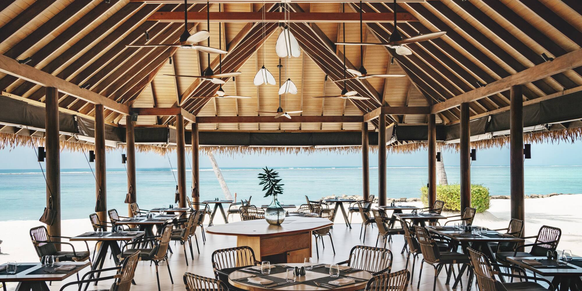 a room with tables and chairs and a view of the ocean