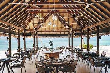 a room with tables and chairs and a view of the ocean