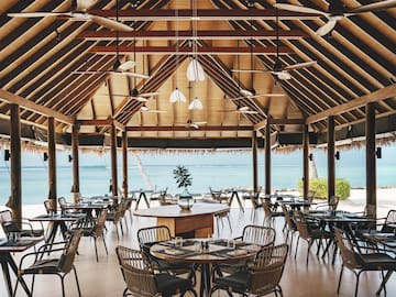 a room with tables and chairs and a view of the ocean