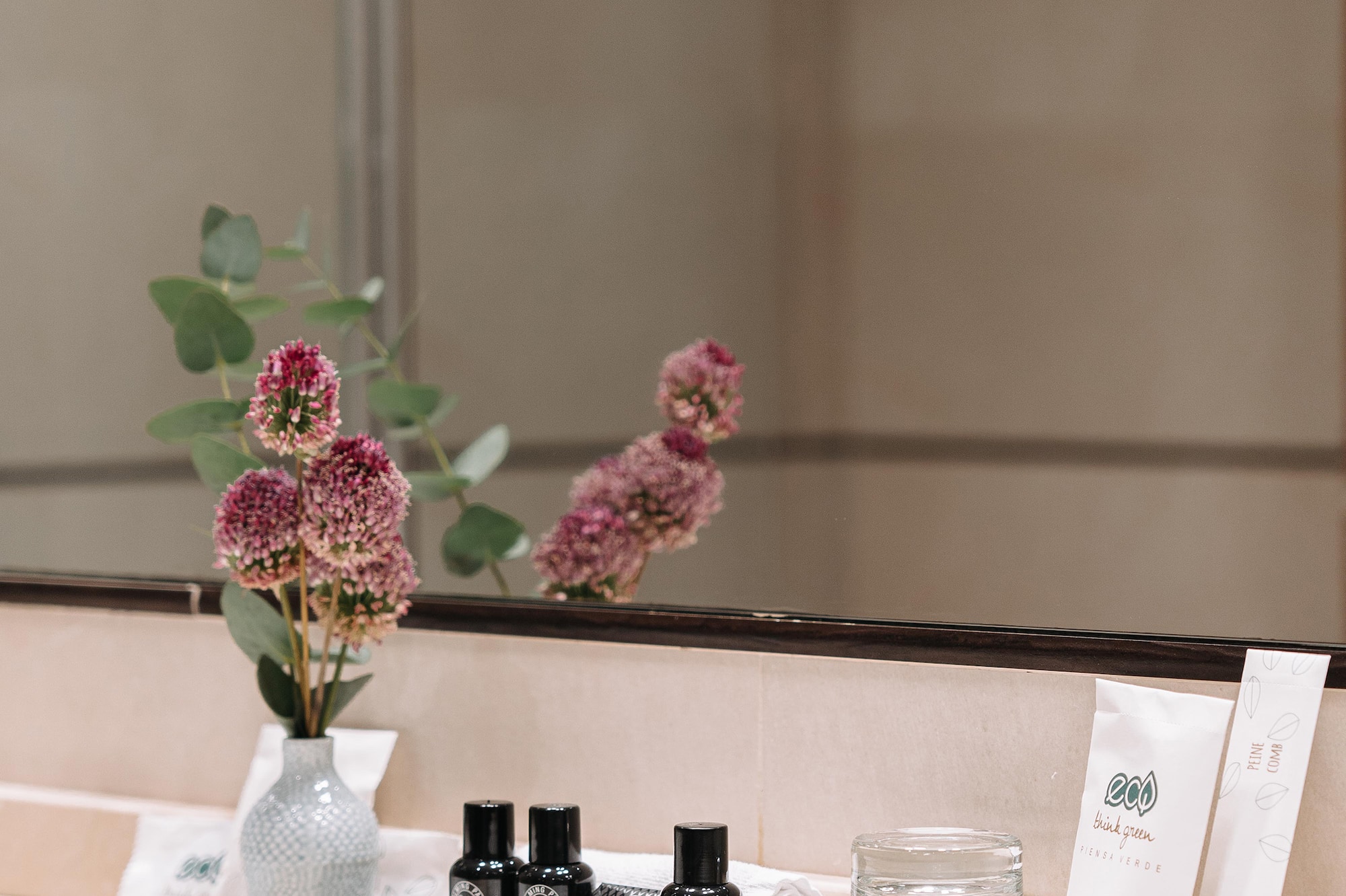 a bathroom mirror with a vase of flowers and other objects