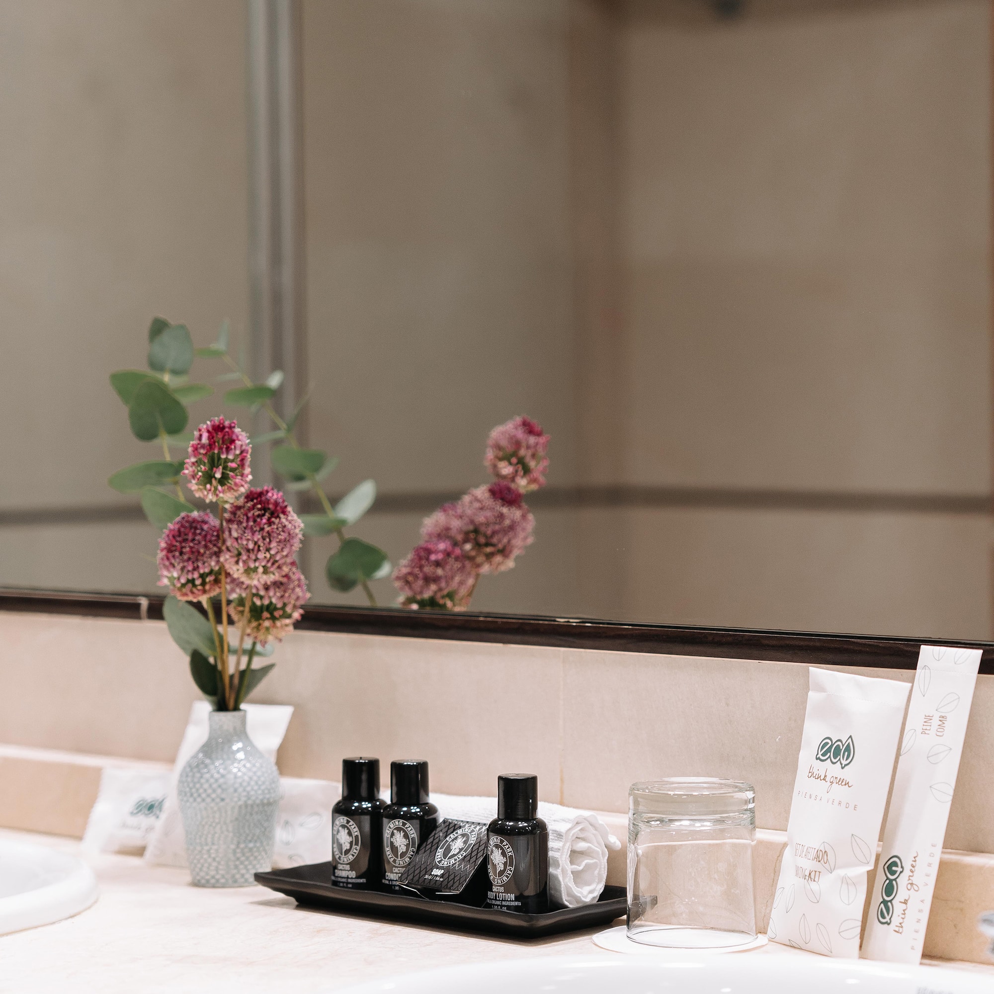a bathroom mirror with a vase of flowers and other objects