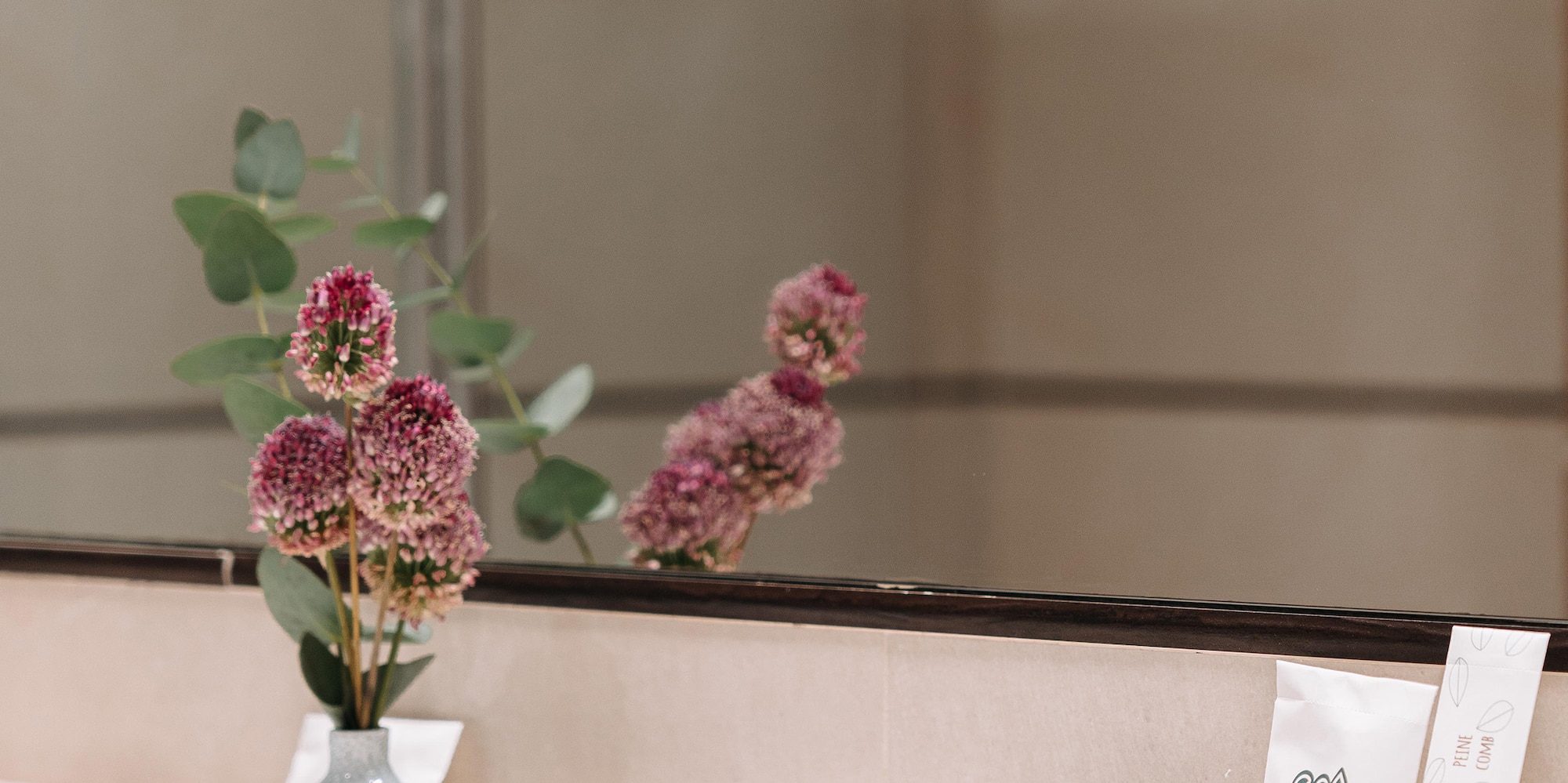 a bathroom mirror with a vase of flowers and other objects