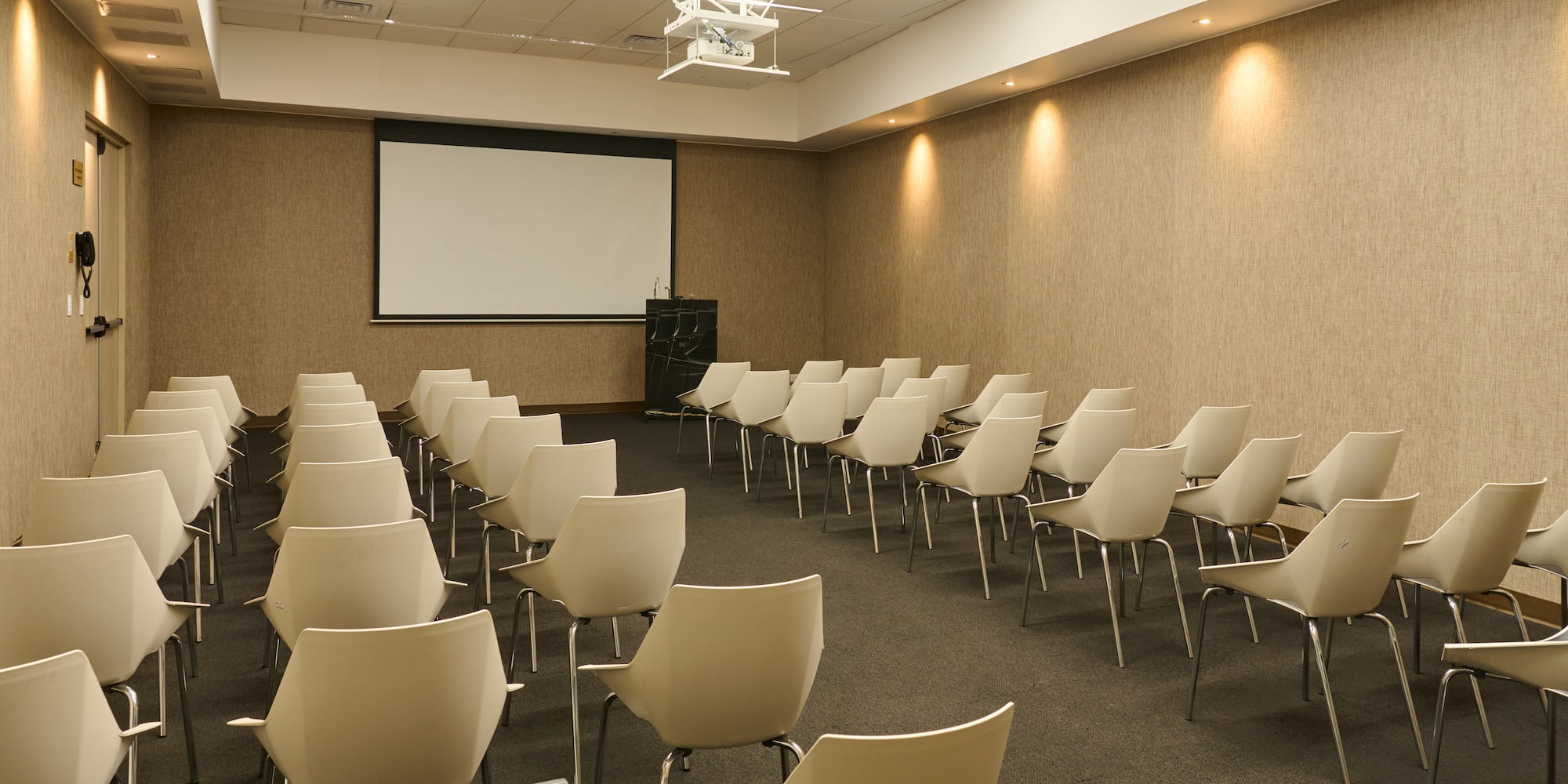 a room with white chairs and a projector screen
