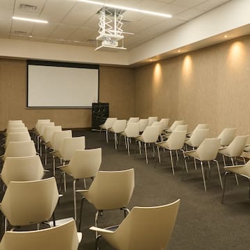 a room with white chairs and a projector screen