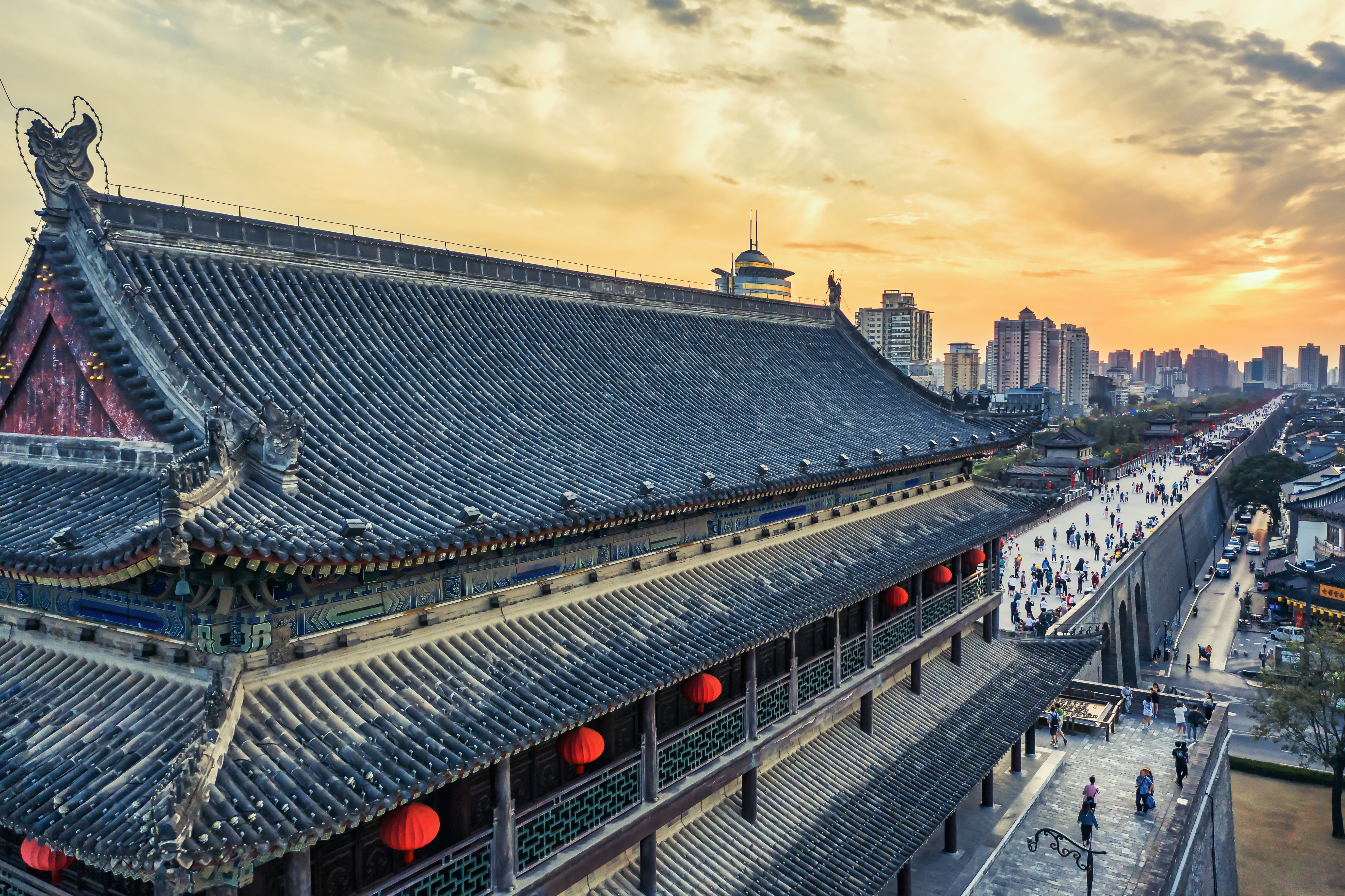 a building with a large roof and people walking on the sidewalk