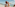 Smiling man lifts happy child high on a sunny beach by the ocean.
